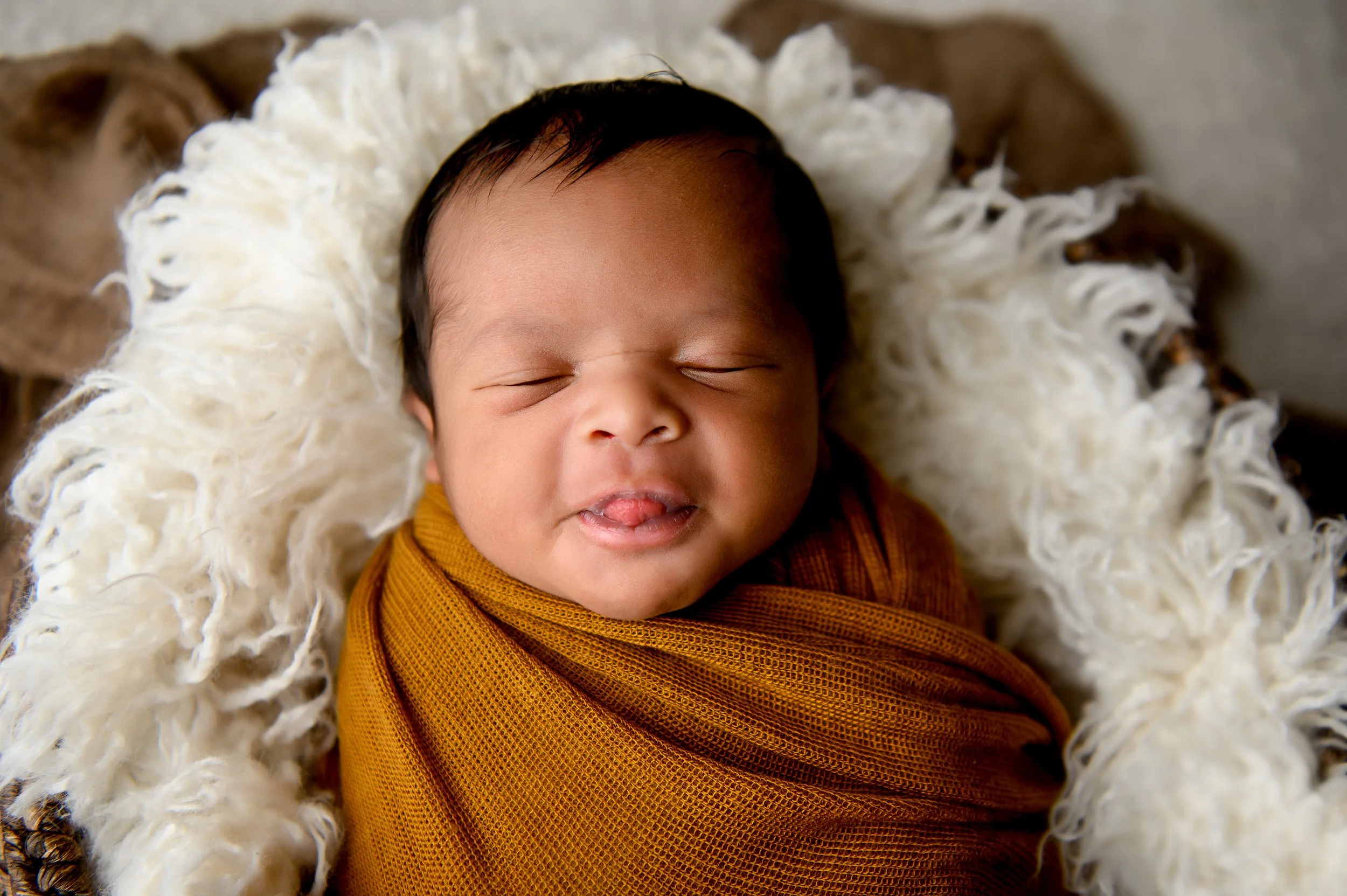 Newborn baby wrapped in warm caramel tones during a newborn portrait session with Crystal Artis Photography in Atlanta, Georgia.