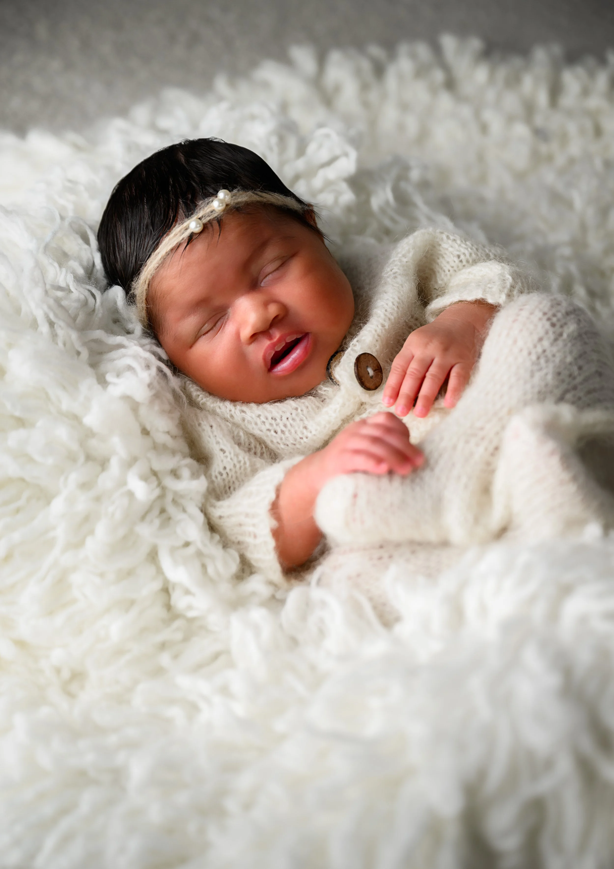 Newborn baby girl sleeping in a cream knit outfit during an Atlanta newborn portrait session.