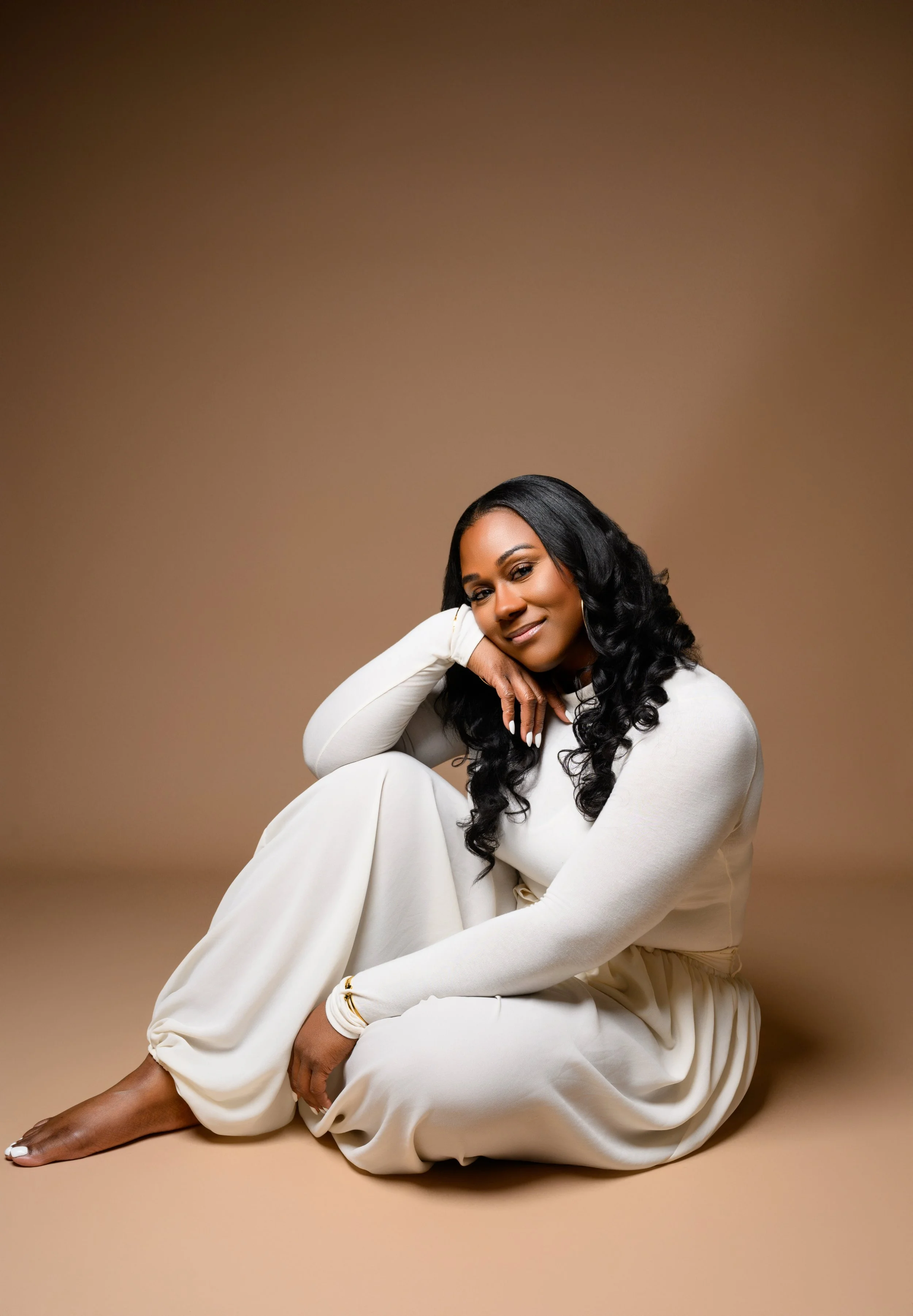 Tempestt seated in a cream outfit against a warm brown studio backdrop during her Atlanta portrait session.