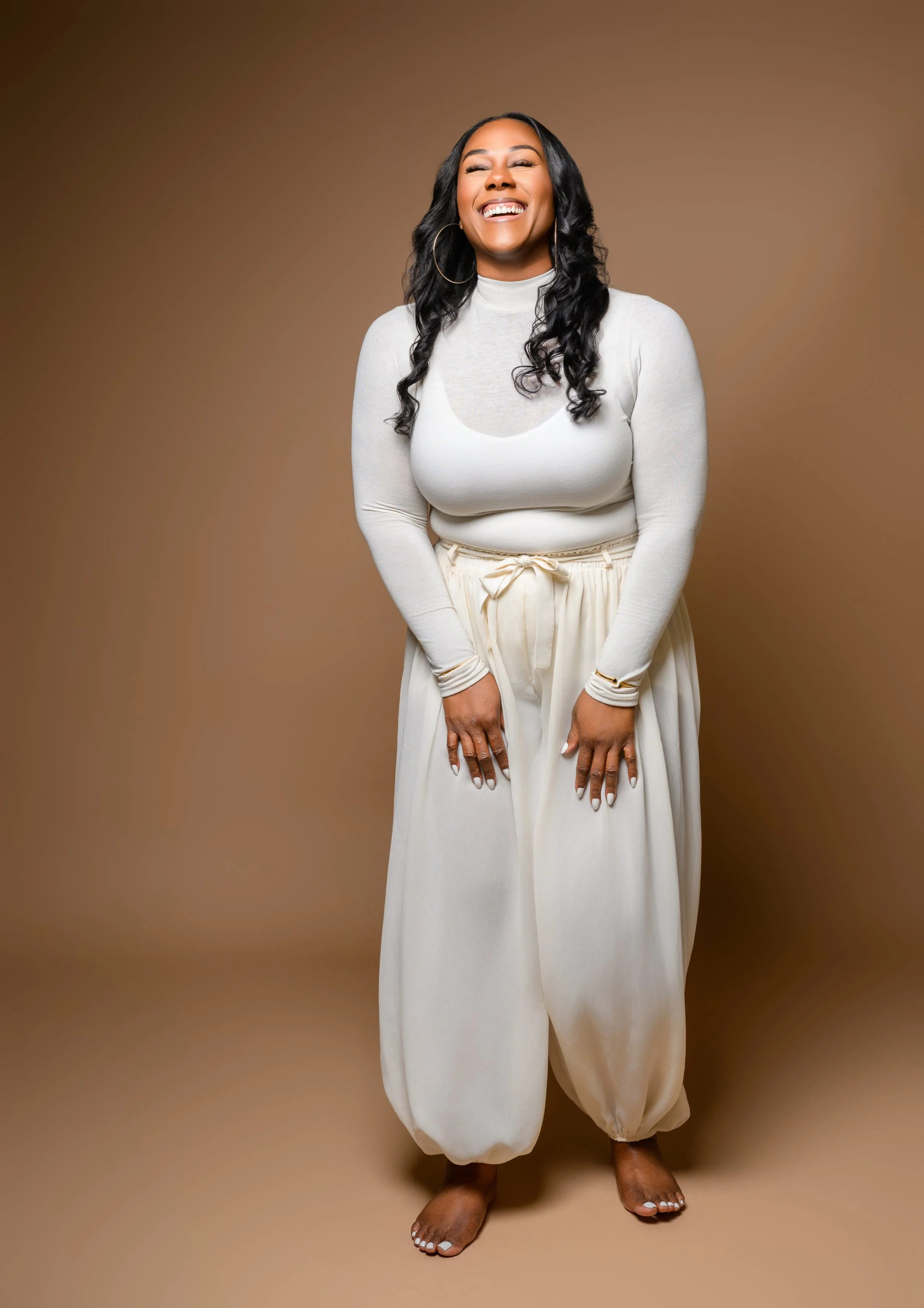 Tempestt laughing in a cream outfit during her milestone portrait session in Atlanta.