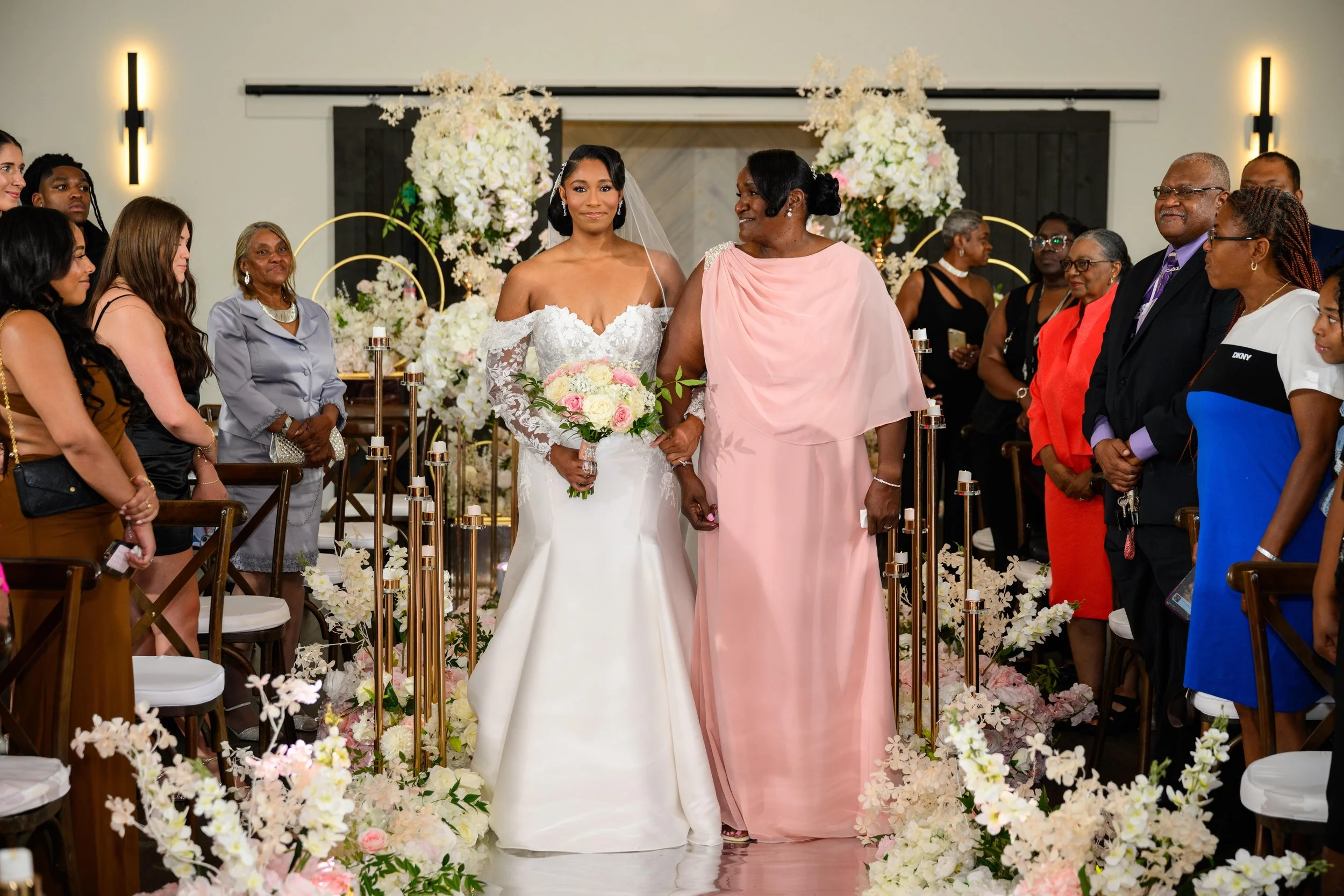 Bride walking down the flower-lined aisle with her mother at The Venue at Daisy Hill.