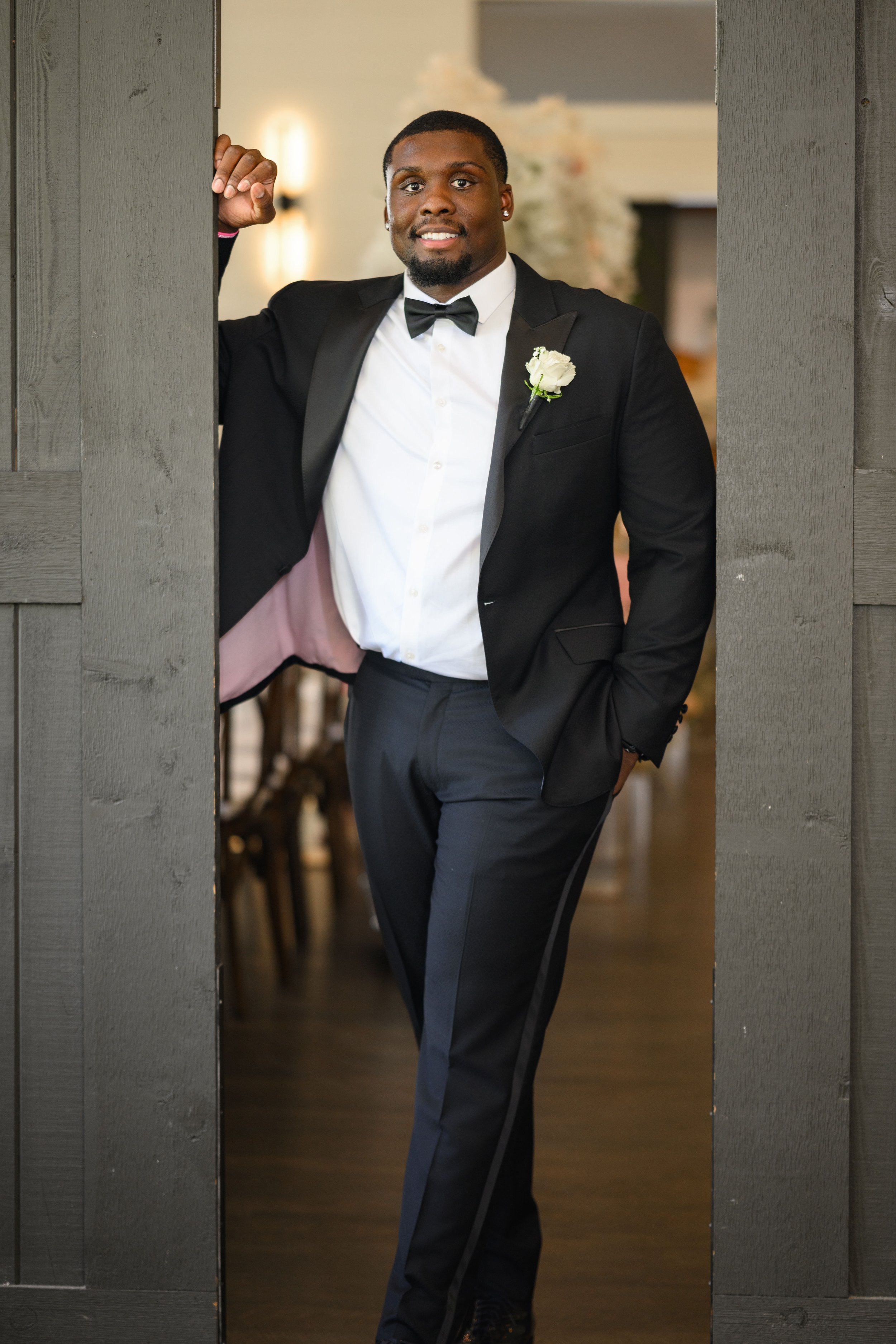 Groom in a black tuxedo posing for a wedding portrait at The Venue at Daisy Hill.