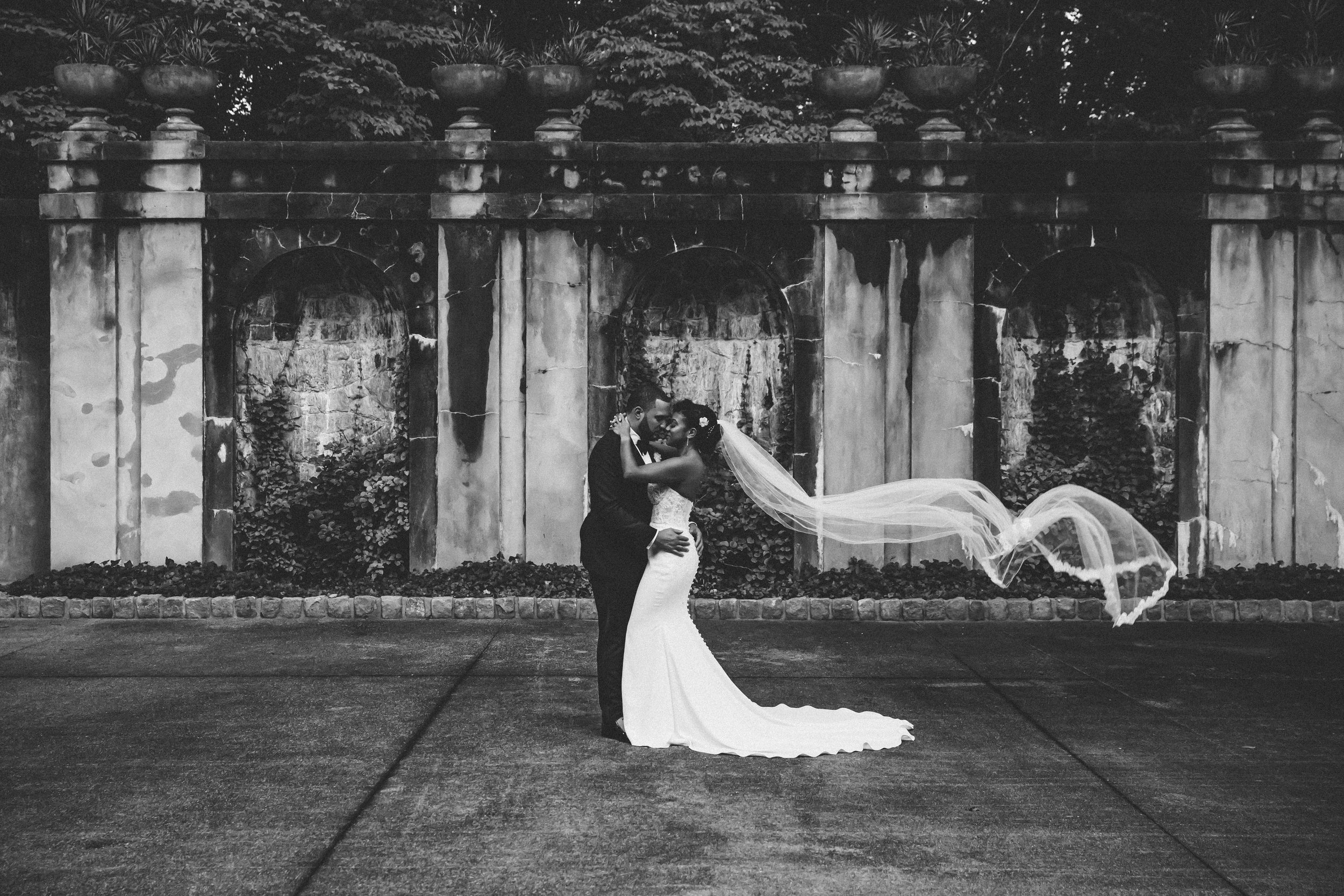 Bride and groom sharing a romantic moment with her veil flowing at the Swan House in Atlanta, photographed by Crystal Artis Photography.