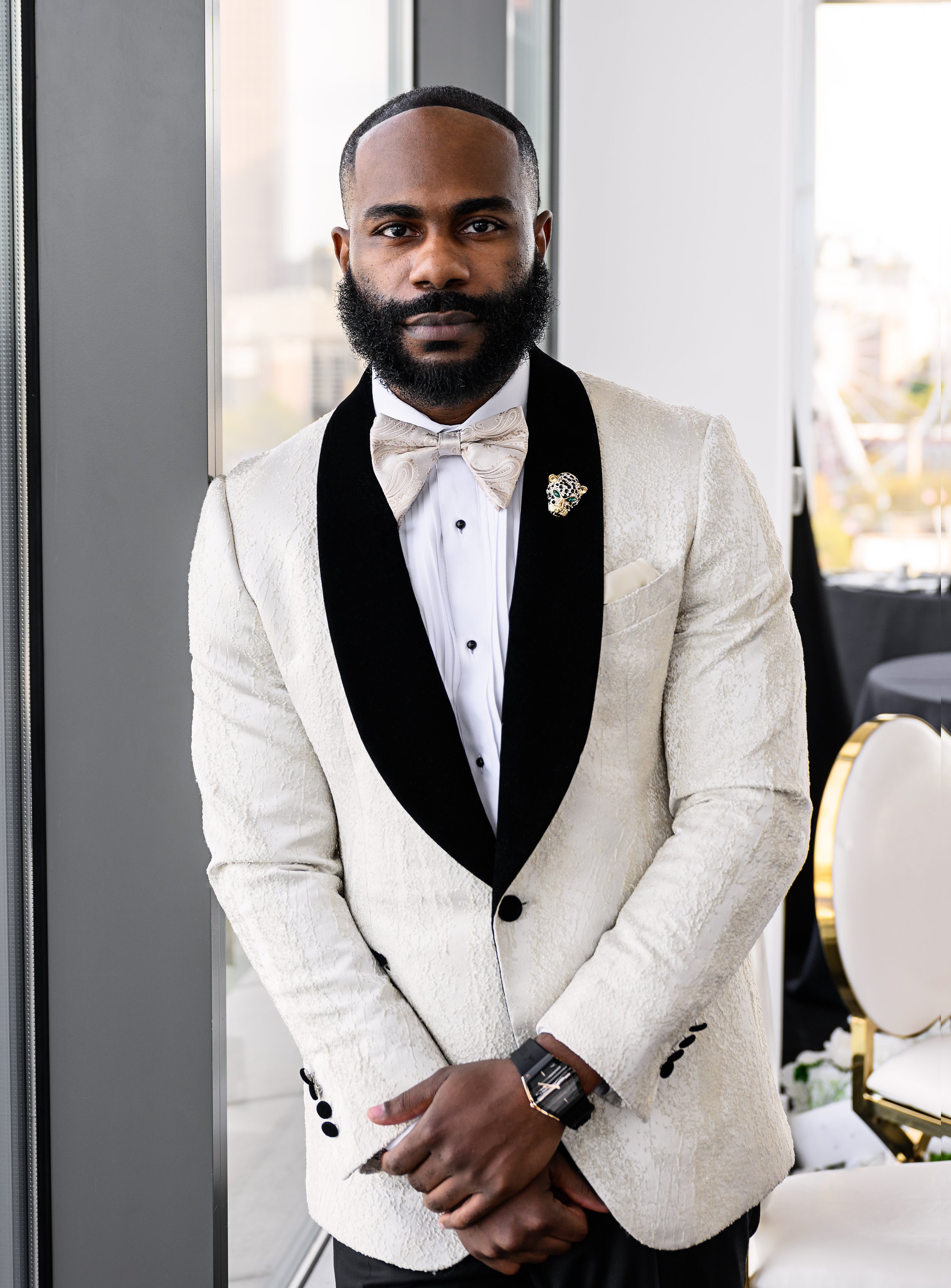 Groom in a white tuxedo jacket posing before his wedding at Ventanas Atlanta.