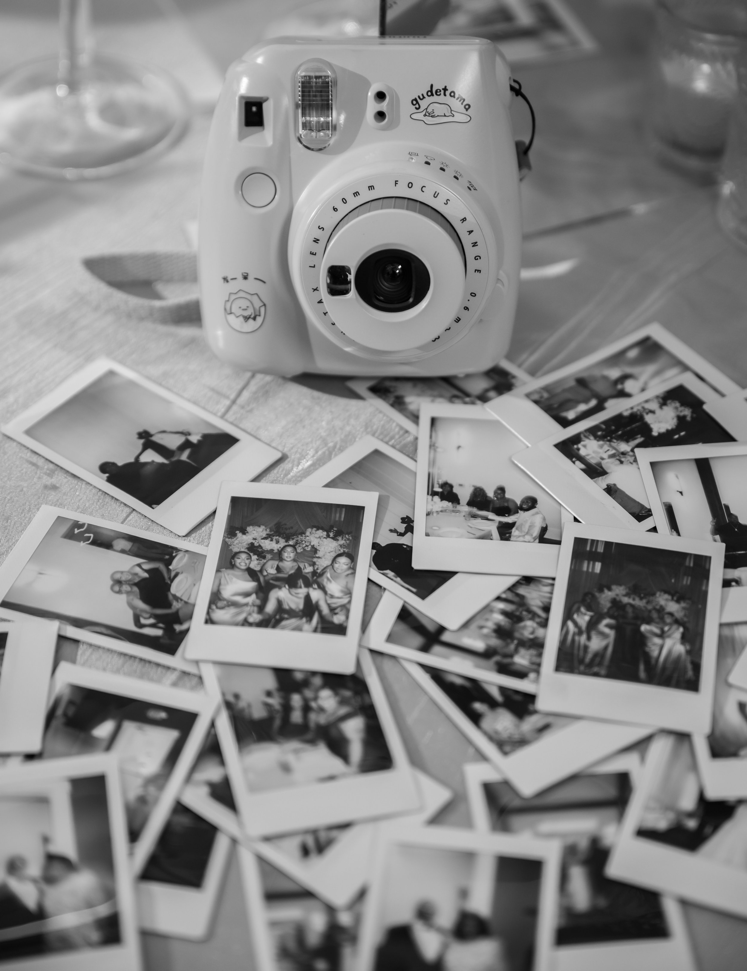 Instant camera surrounded by guest photographs at a wedding reception at The Venue at Daisy Hill.