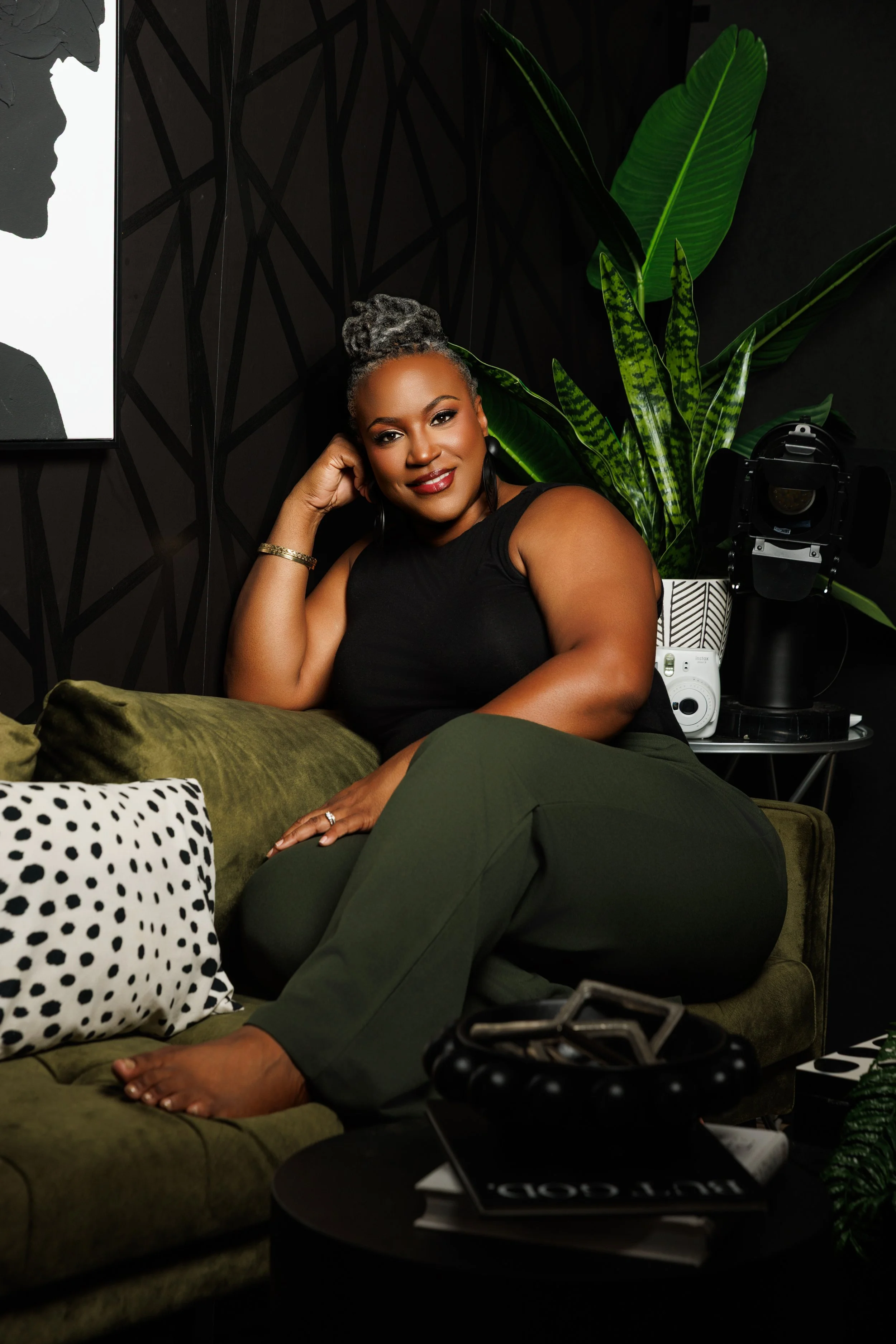 Crystal Artis, Atlanta photographer, seated in studio surrounded by olive green and black decor
