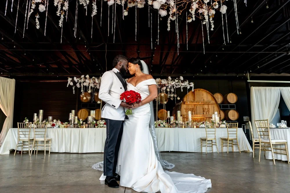Bride and groom posing beneath hanging floral decor during their wedding reception at Chateau Elan in Braselton, Georgia, photographed by Crystal Artis Photography.
