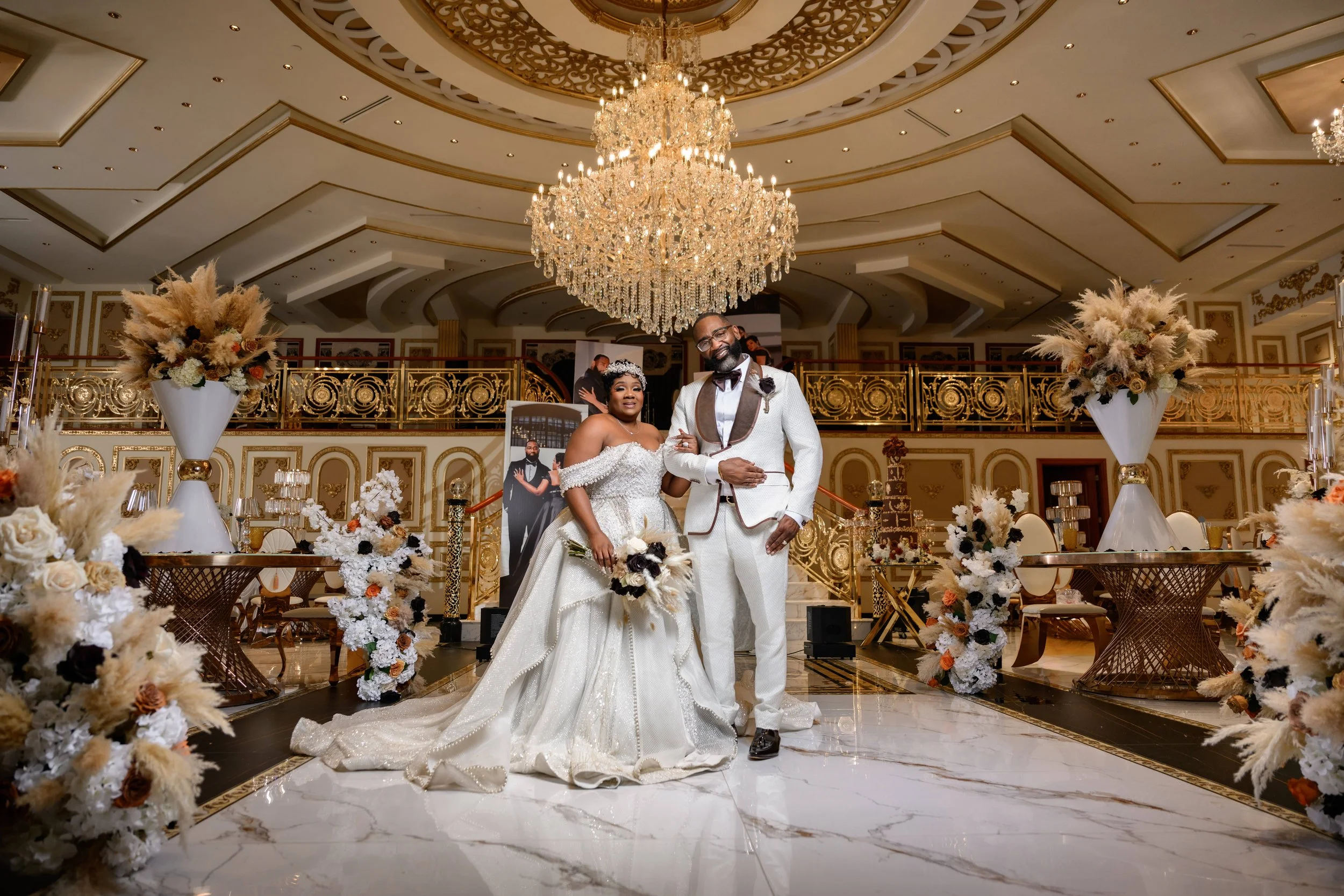 Bride and groom posing beneath a crystal chandelier inside Shahbain Events Center in North Carolina.