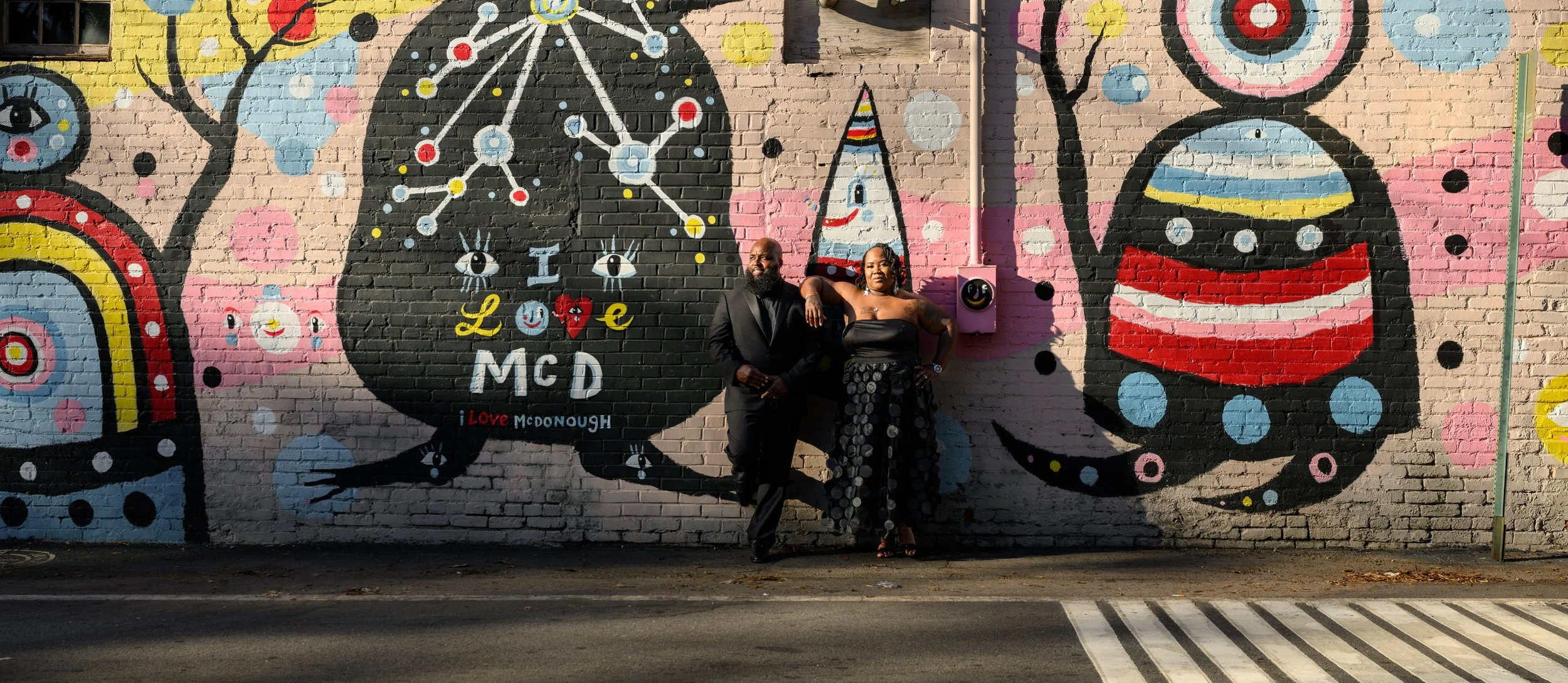 Couple posing in front of a colorful mural during a photo session in downtown McDonough, Georgia.