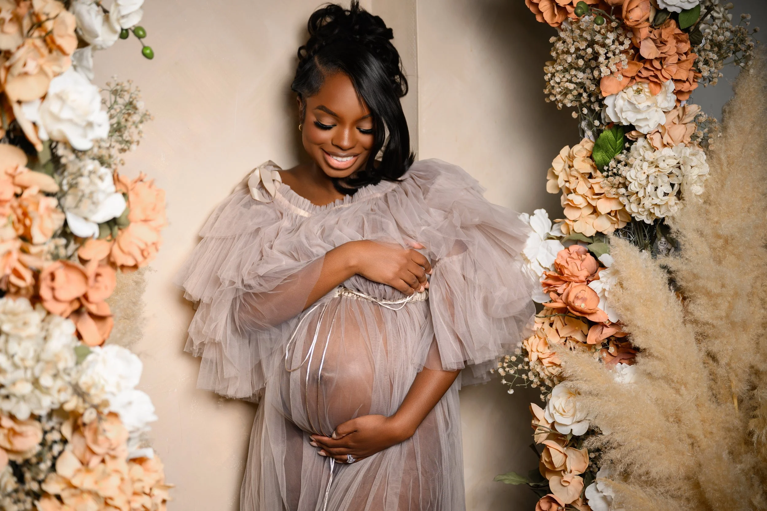 Expecting mother looking down at her baby bump during a floral studio maternity portrait session in Atlanta.