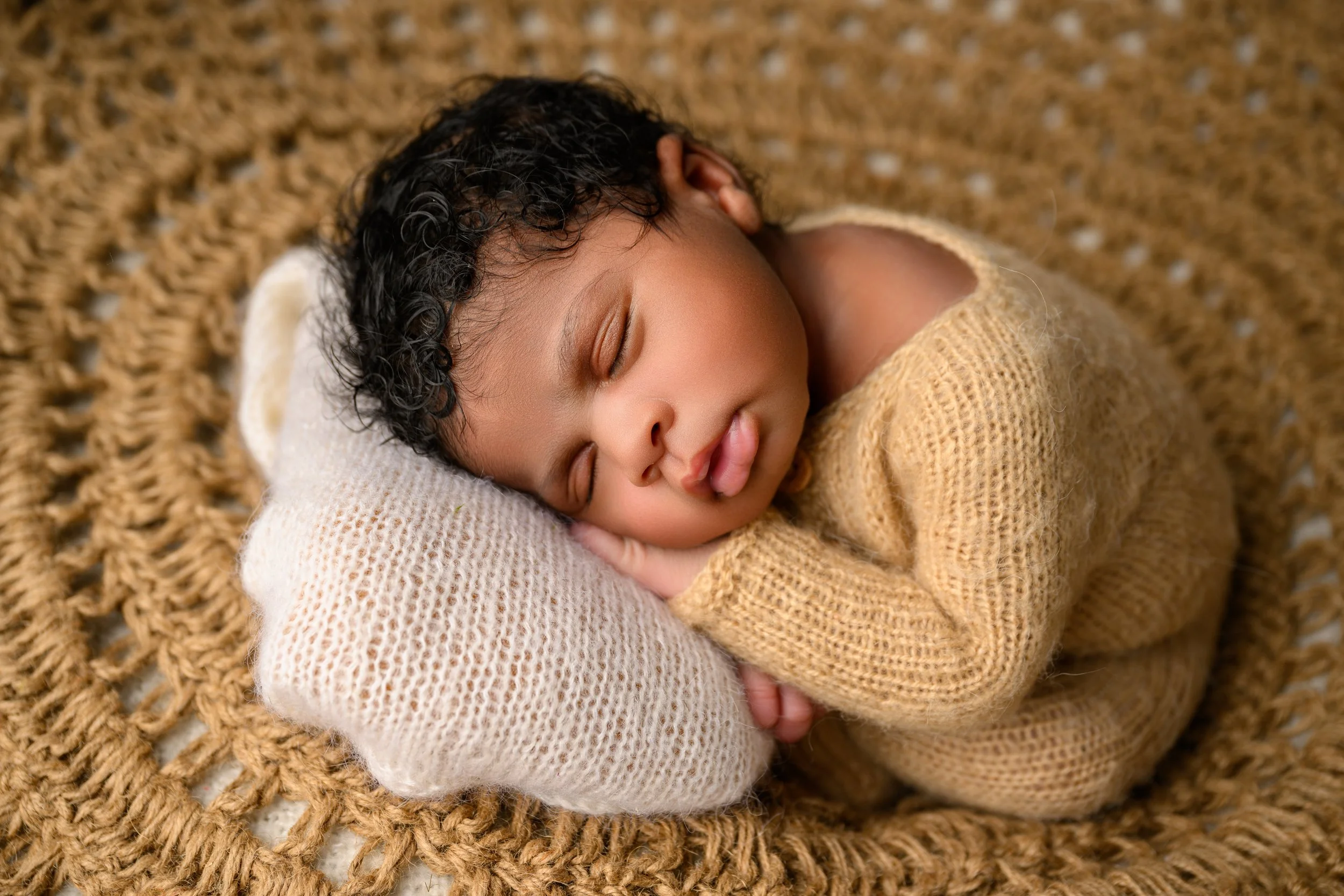 Newborn baby peacefully sleeping in a warm neutral wrap during an Atlanta newborn photography session