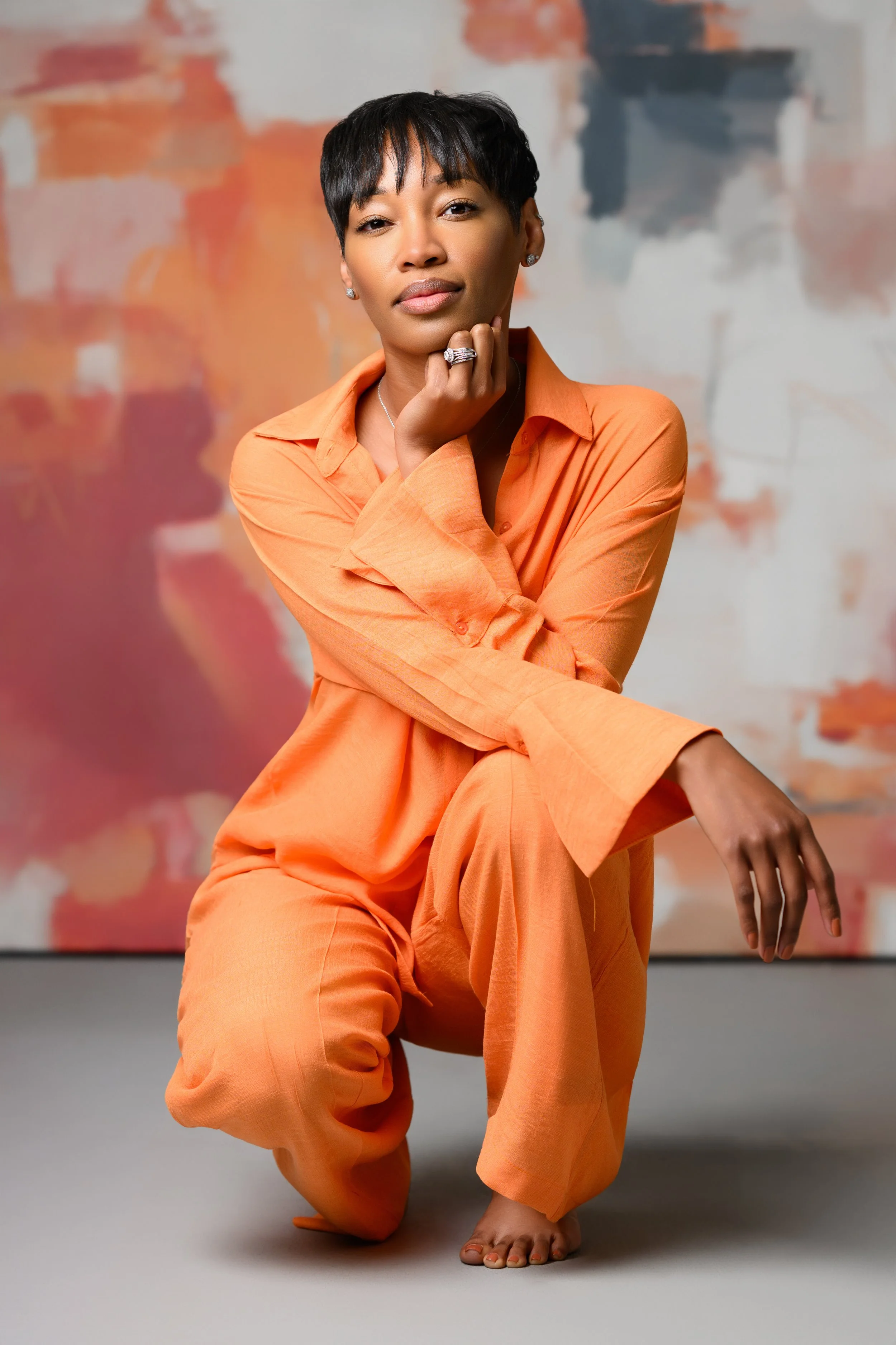 Woman in a vibrant orange outfit posing during a studio portrait session in Atlanta by Crystal Artis Photography.