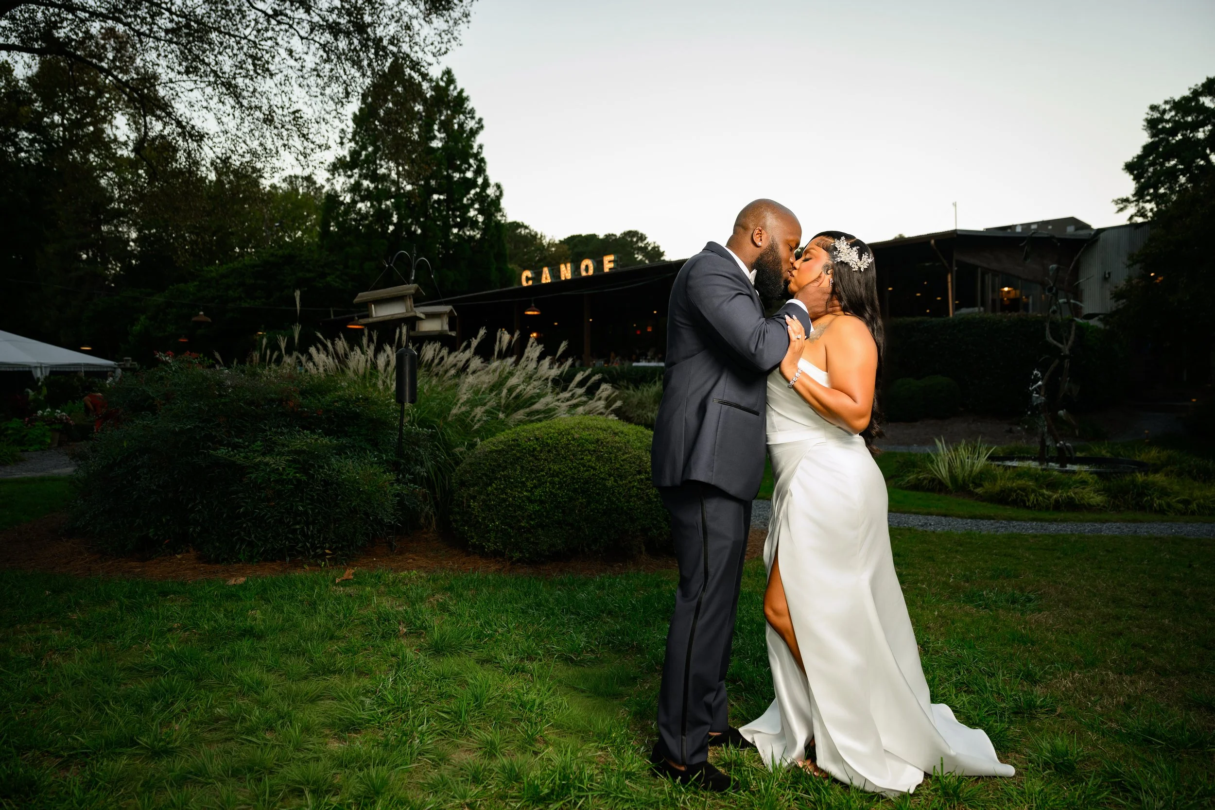 Bride and groom sharing a kiss on the lawn outside Canoe Restaurant during their intimate October wedding in Atlanta.