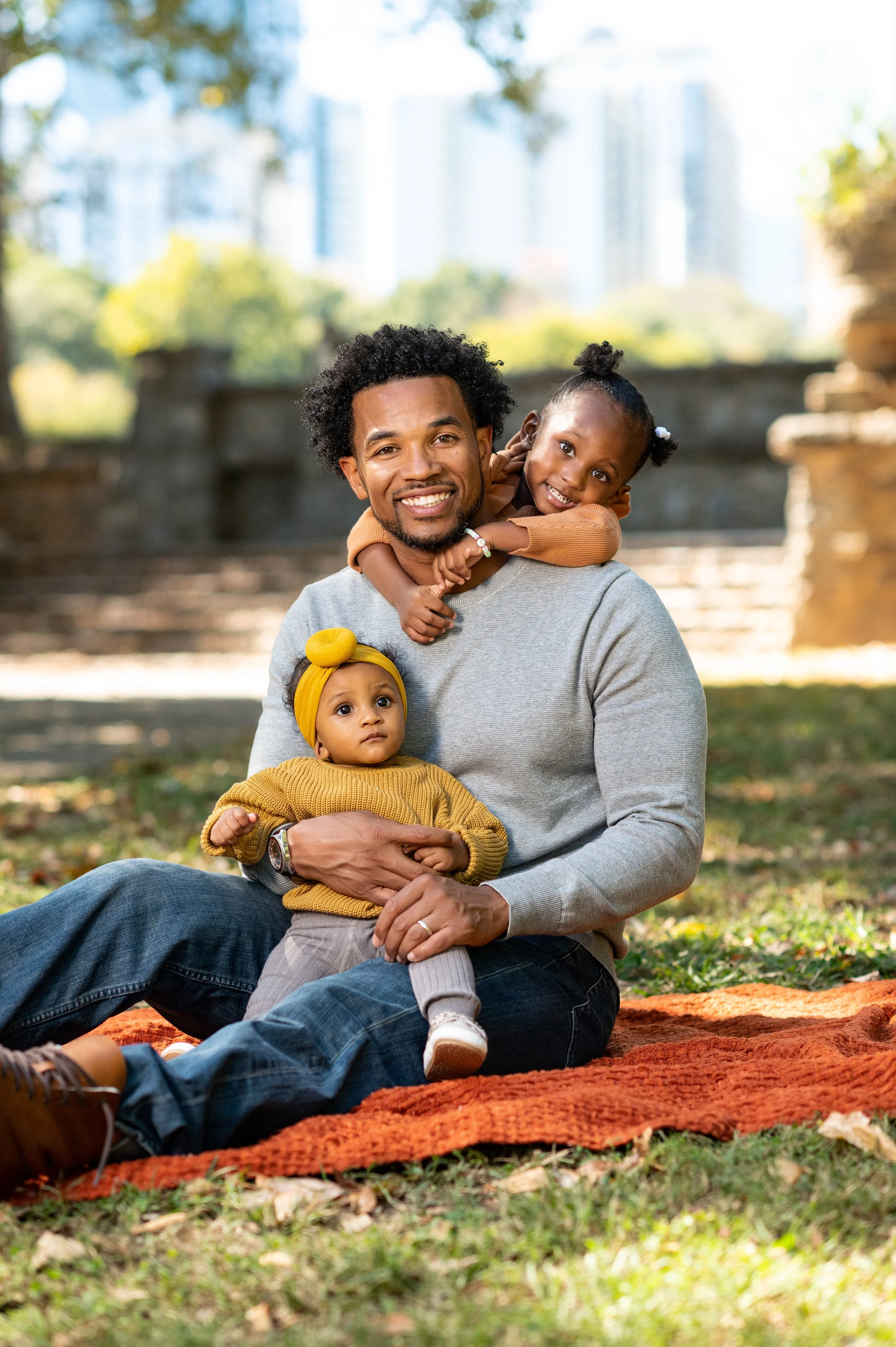 Father with his two daughters during an outdoor family portrait session at Piedmont Park in Atlanta, Georgia.