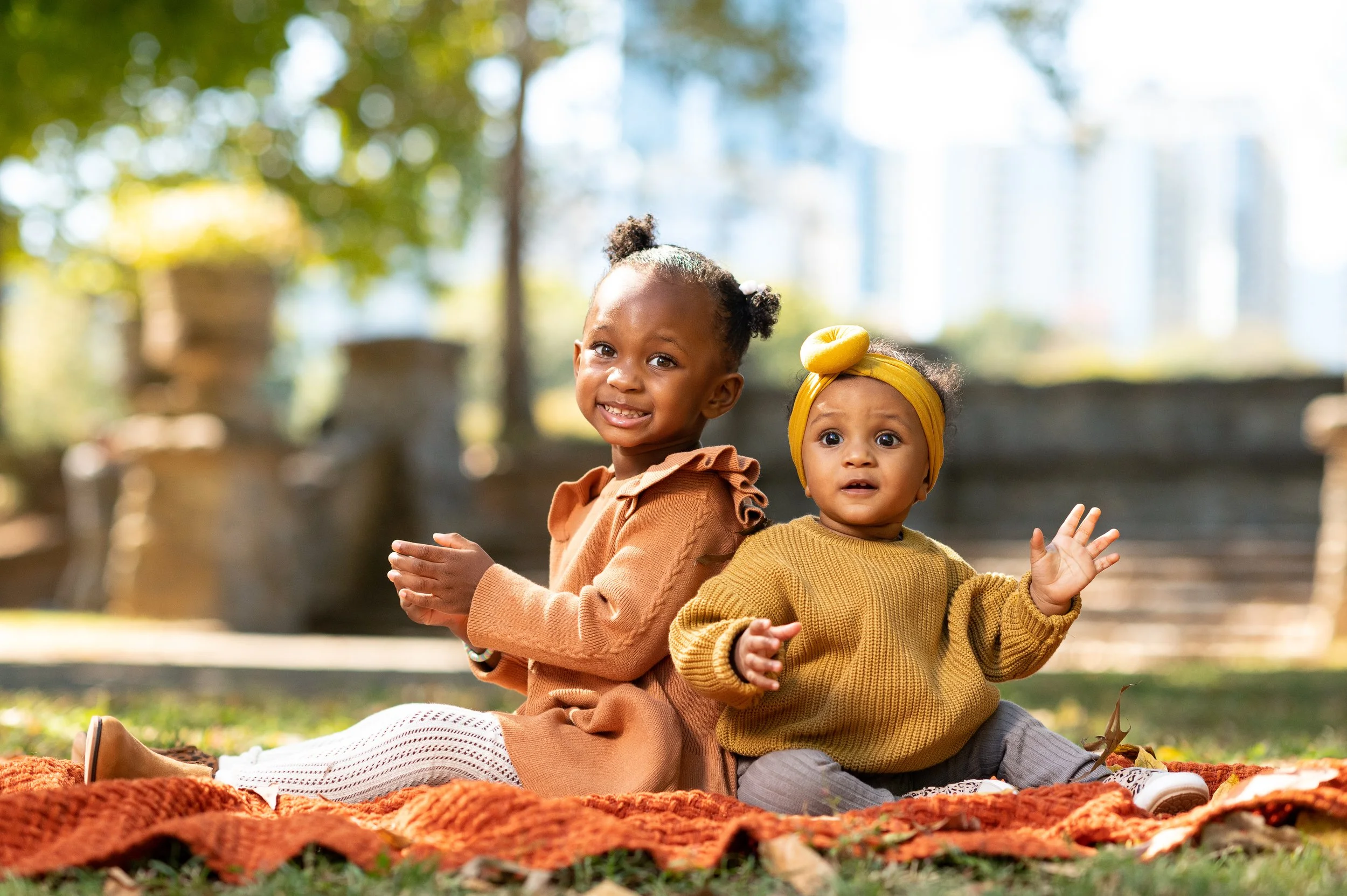 Two sisters smiling together during a fall family portrait session at Piedmont Park in Atlanta, Georgia.