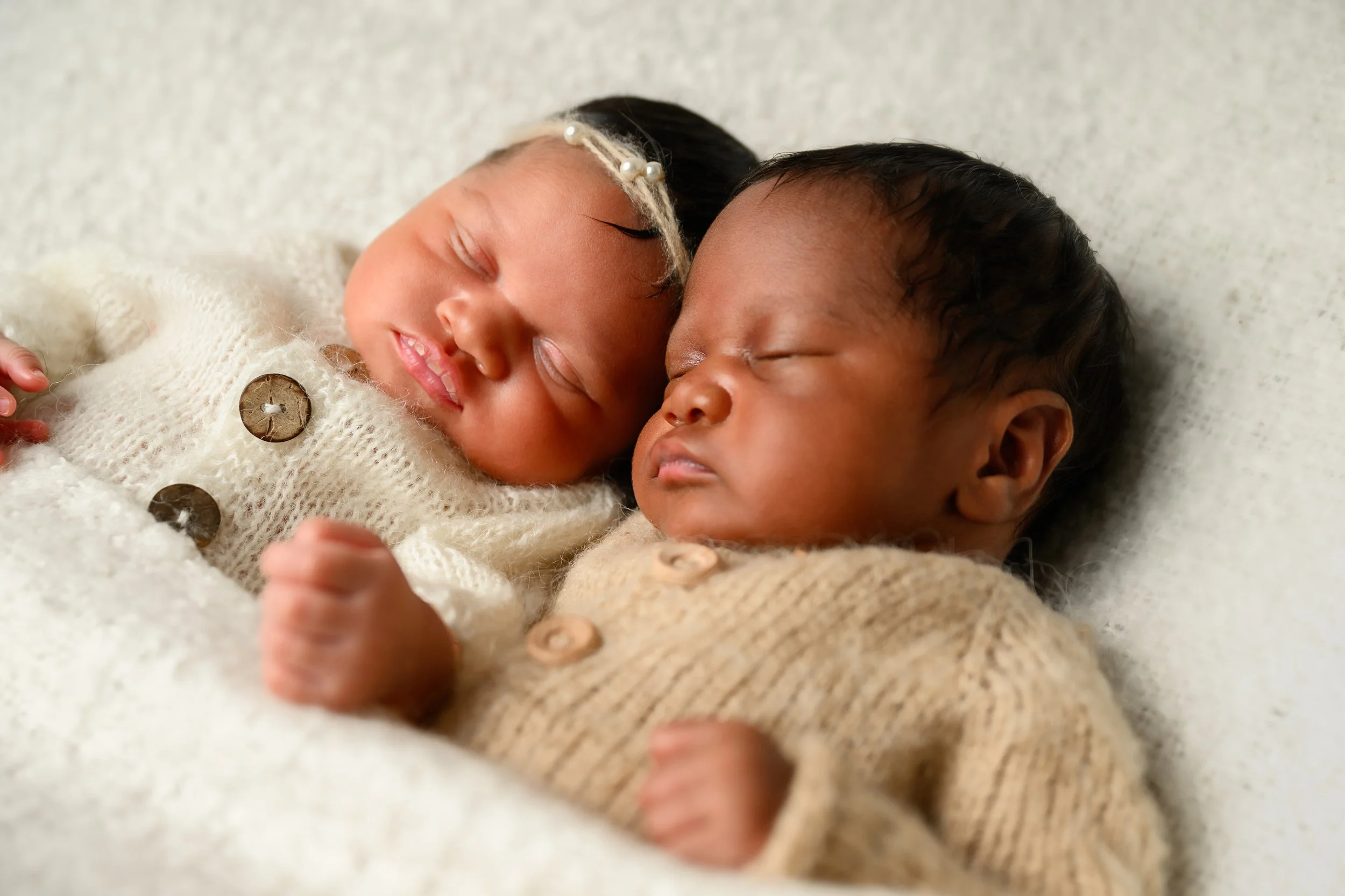 Newborn twins sleeping side-by-side in cream and tan outfits during an Atlanta newborn session.