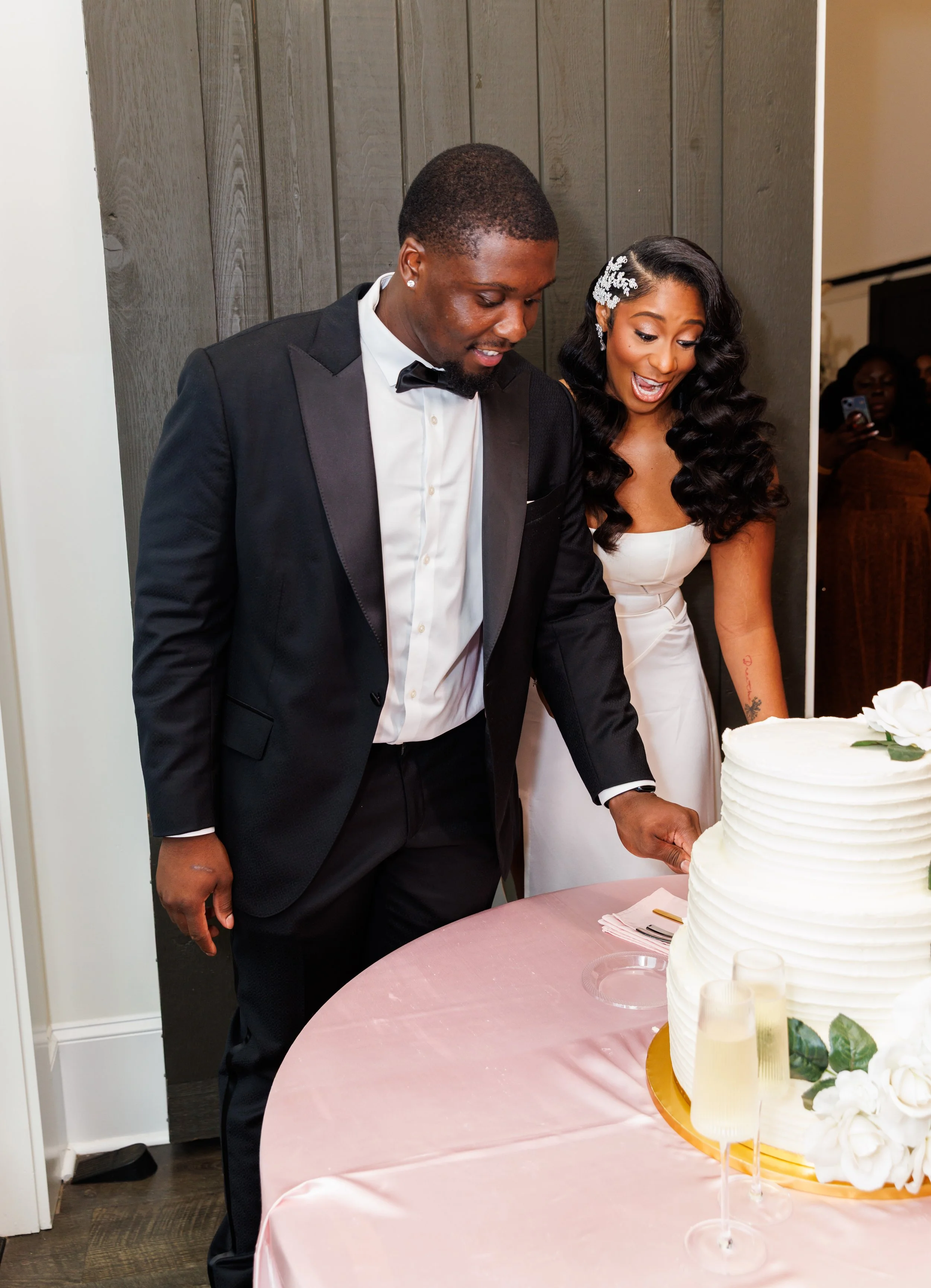 Newlyweds smiling together while cutting their wedding cake at The Venue at Daisy Hill.