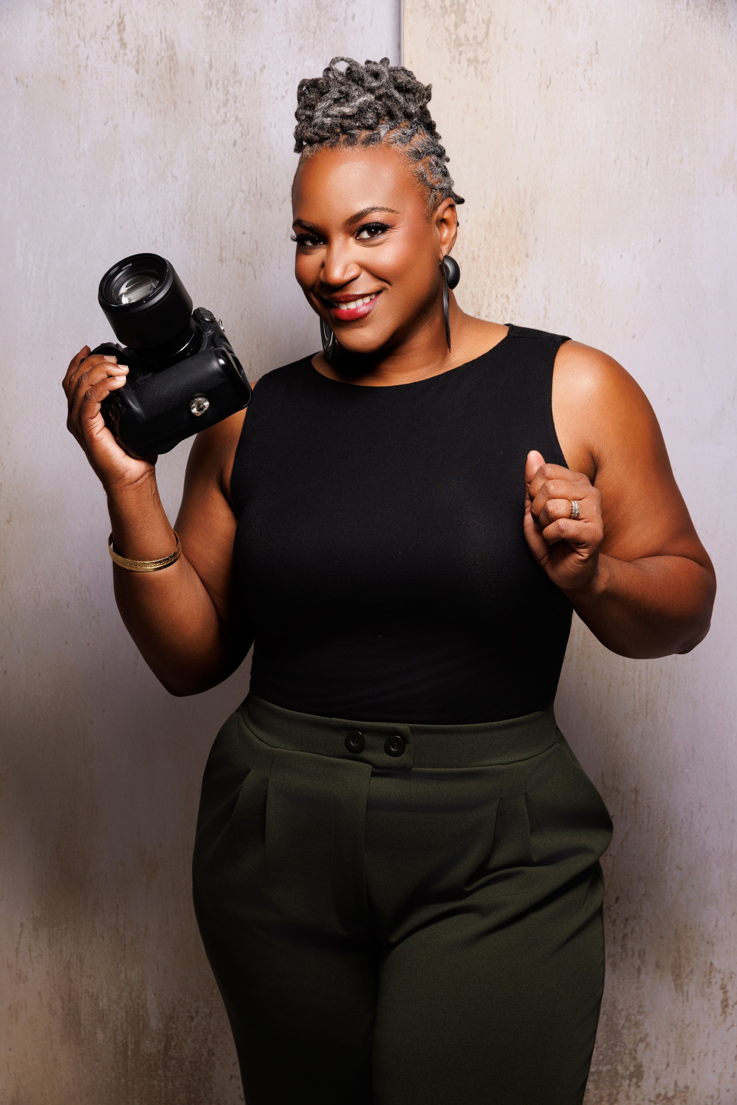 Crystal Artis smiling and holding her camera during a professional branding portrait
