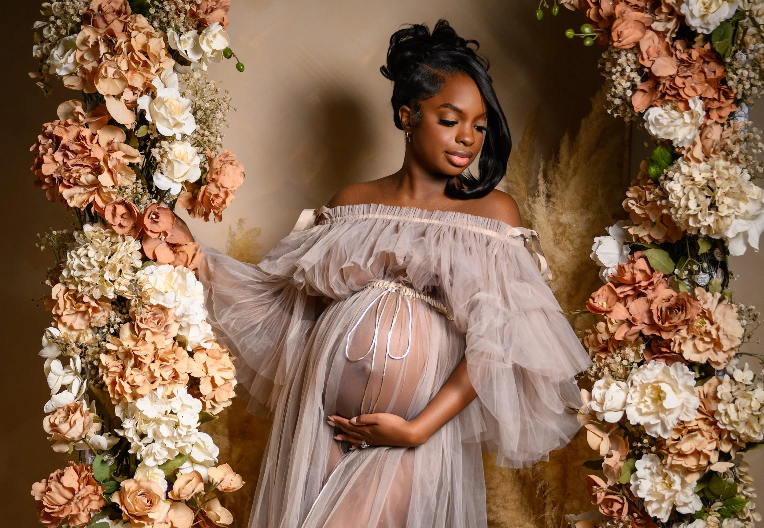 Close maternity portrait of an expecting mother surrounded by warm floral details during a studio session in Atlanta.