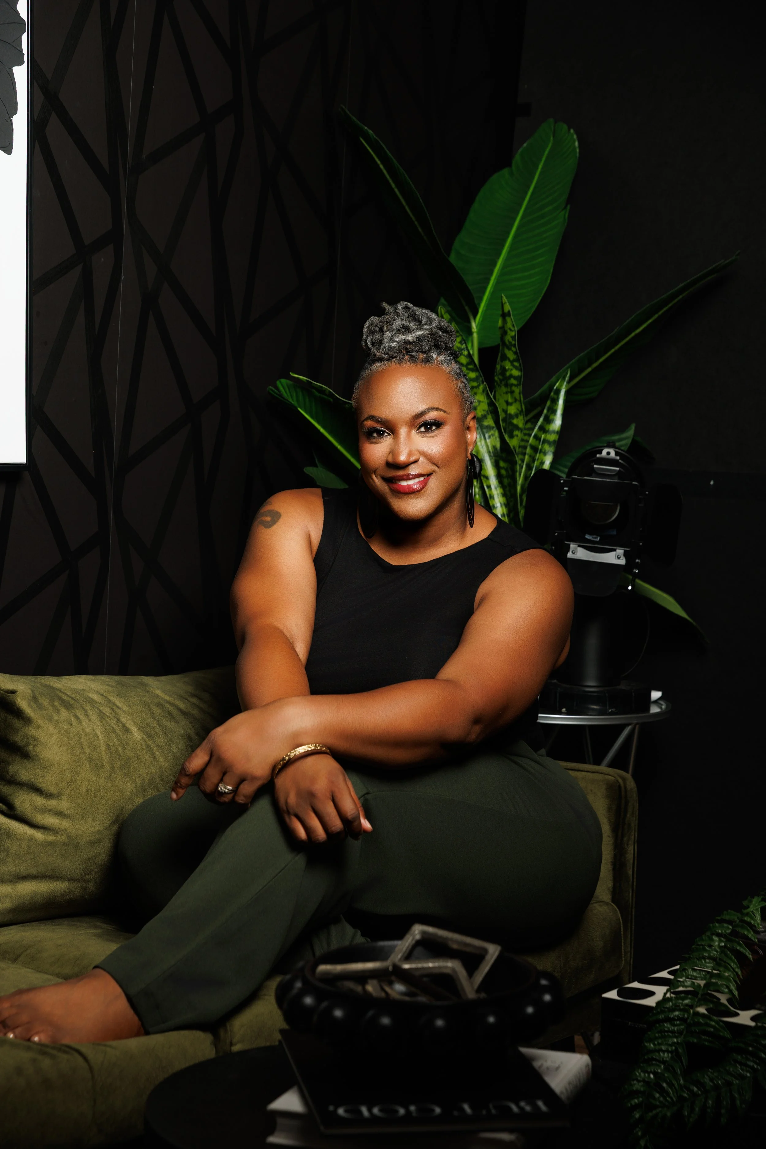 Crystal Artis relaxing in a McDonough studio beside green plants and photography equipment