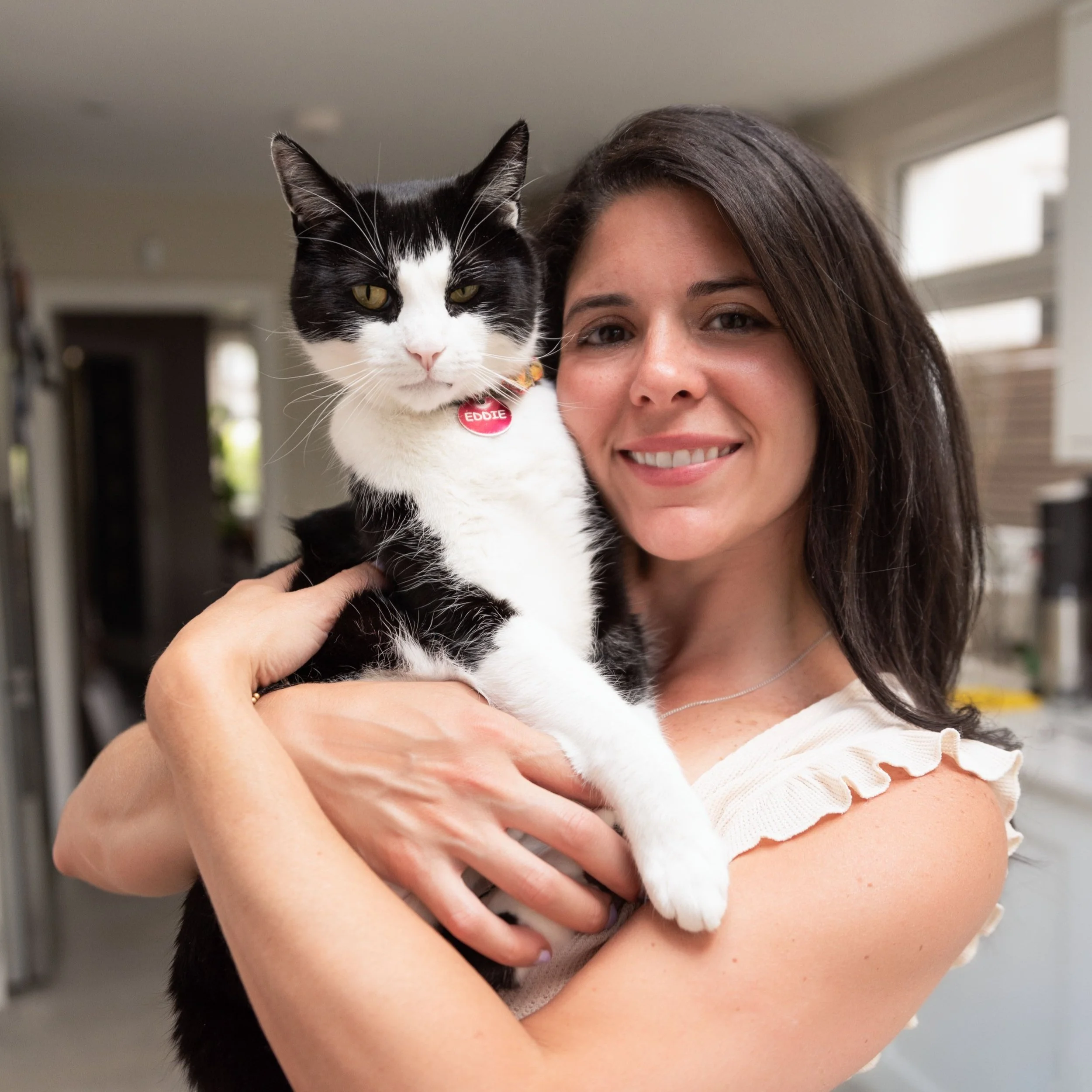 Eco-friendly candle-maker, holds her cat whilst smiles looking at the camera