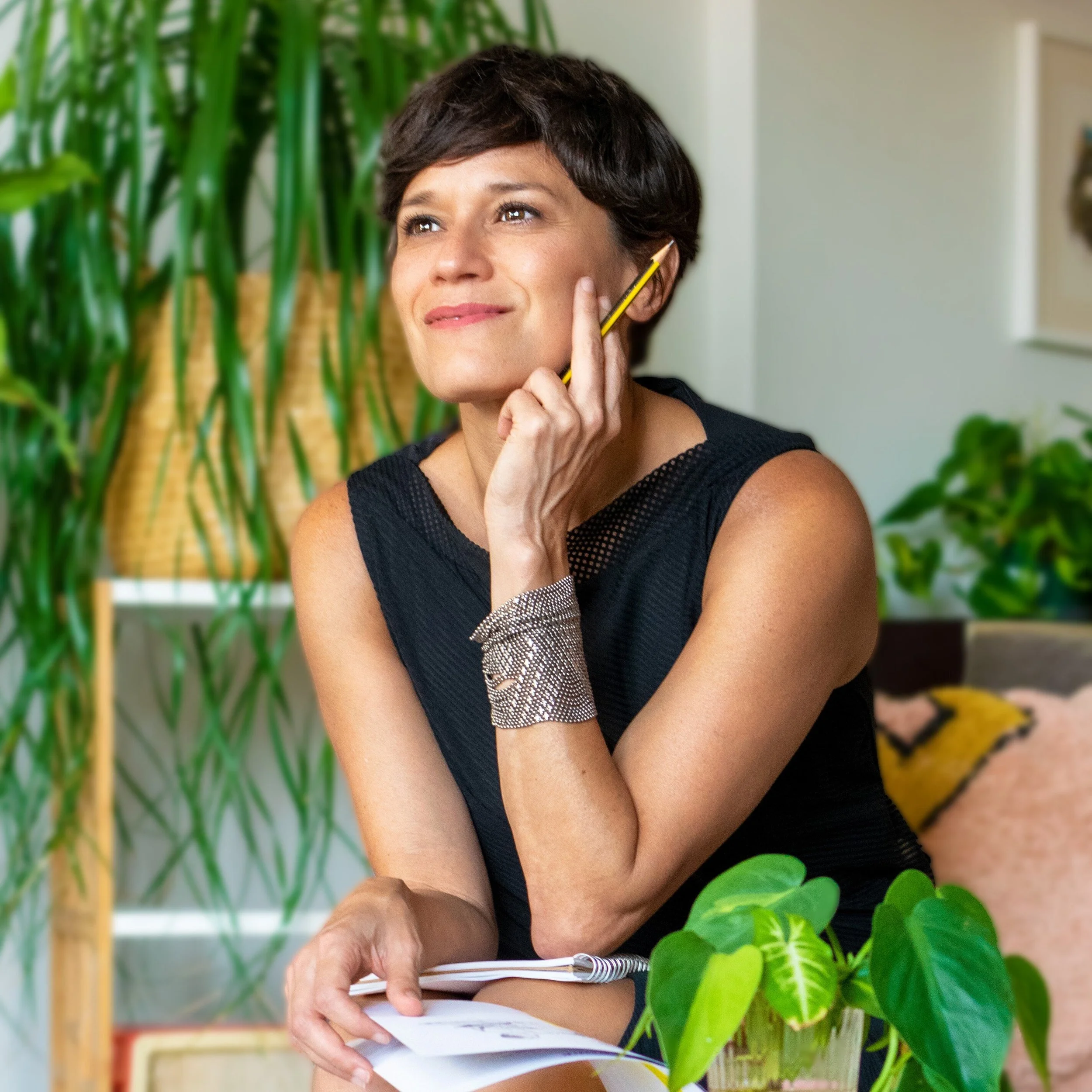 Nathalie with notepad and book, looking up, smiling and inspired