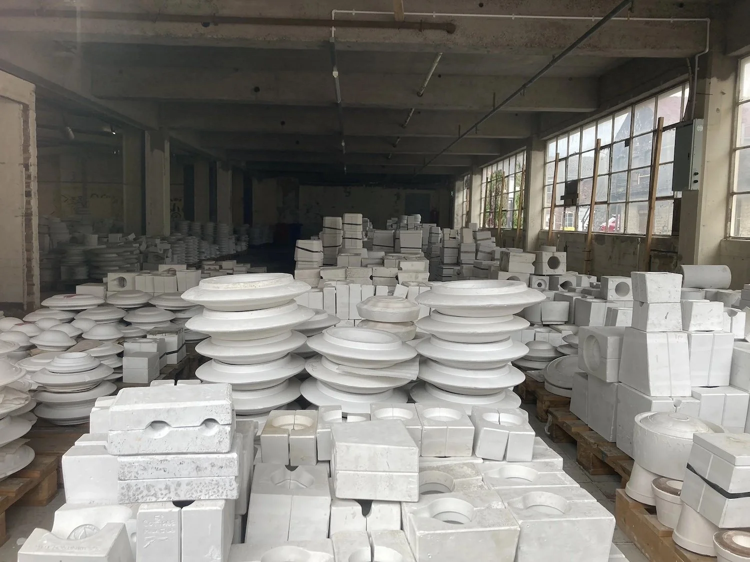 Photograph taken at derelict Spode Pottery Works for essay Waiting Space by ALT-Architecture Situated Studio. Derelict factory space with stacked white moulds.