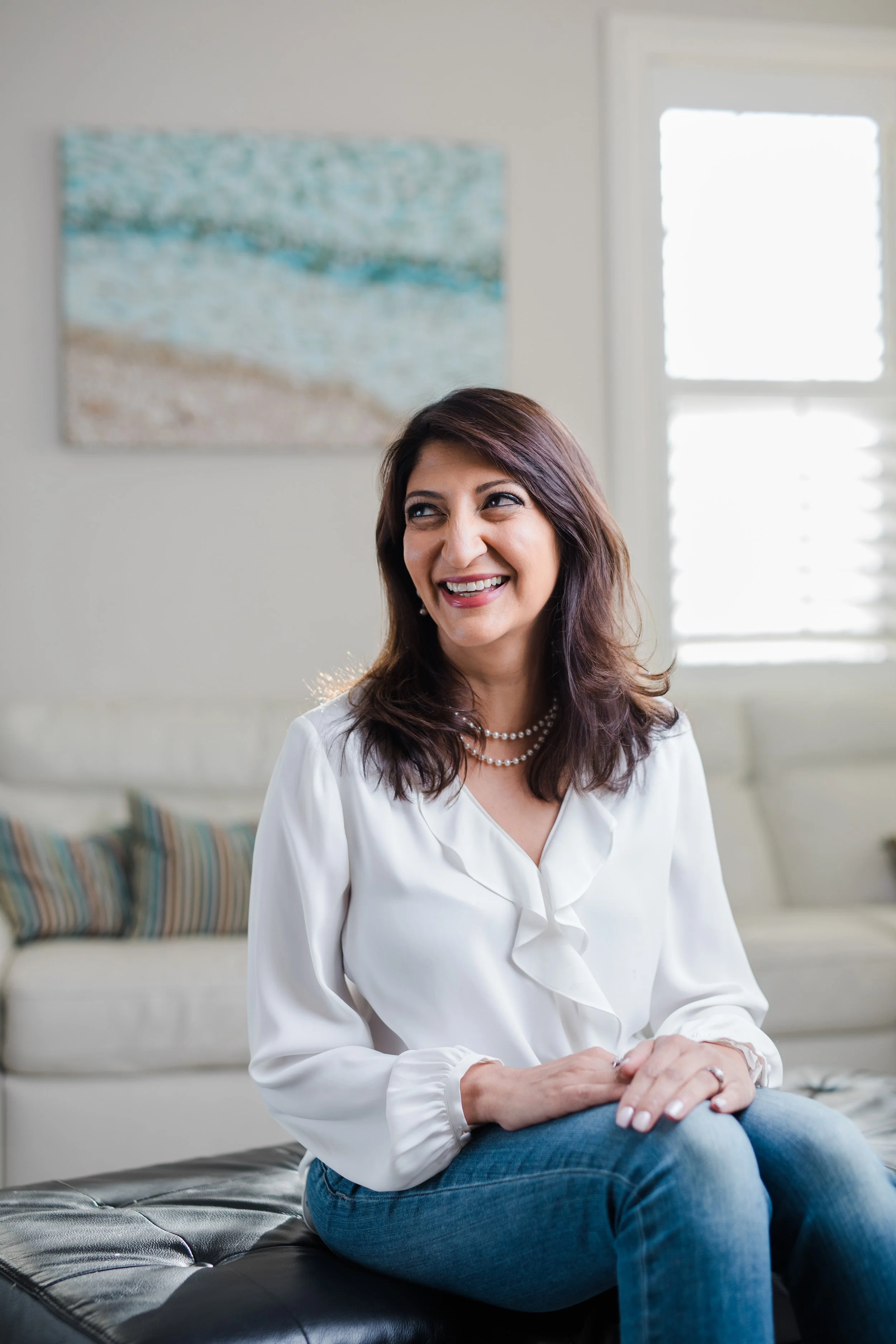 Dr. Gupta poses for a headshot on a couch.