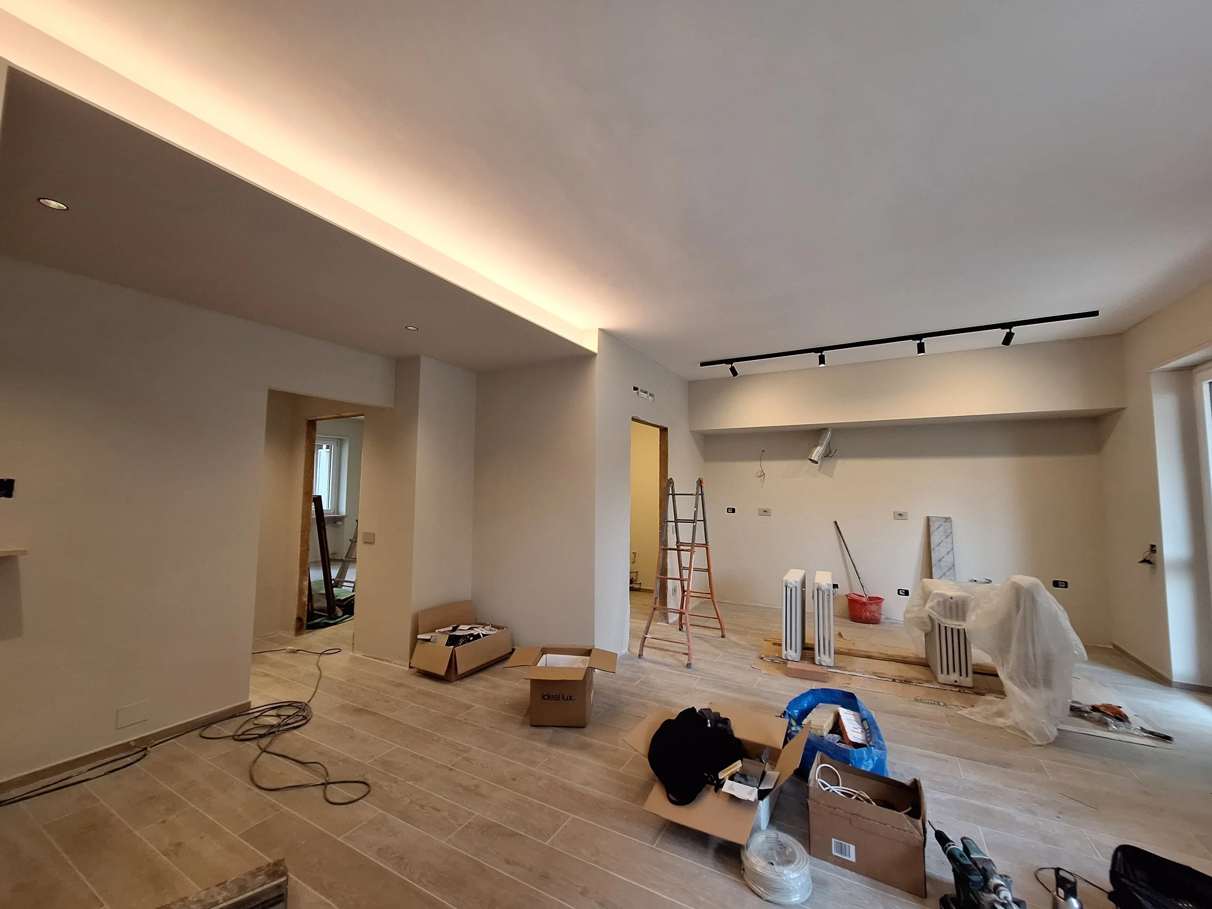 Interno di una casa in fase di ristrutturazione con strumenti e materiali sparsi, pareti e pavimenti in corso di finitura.