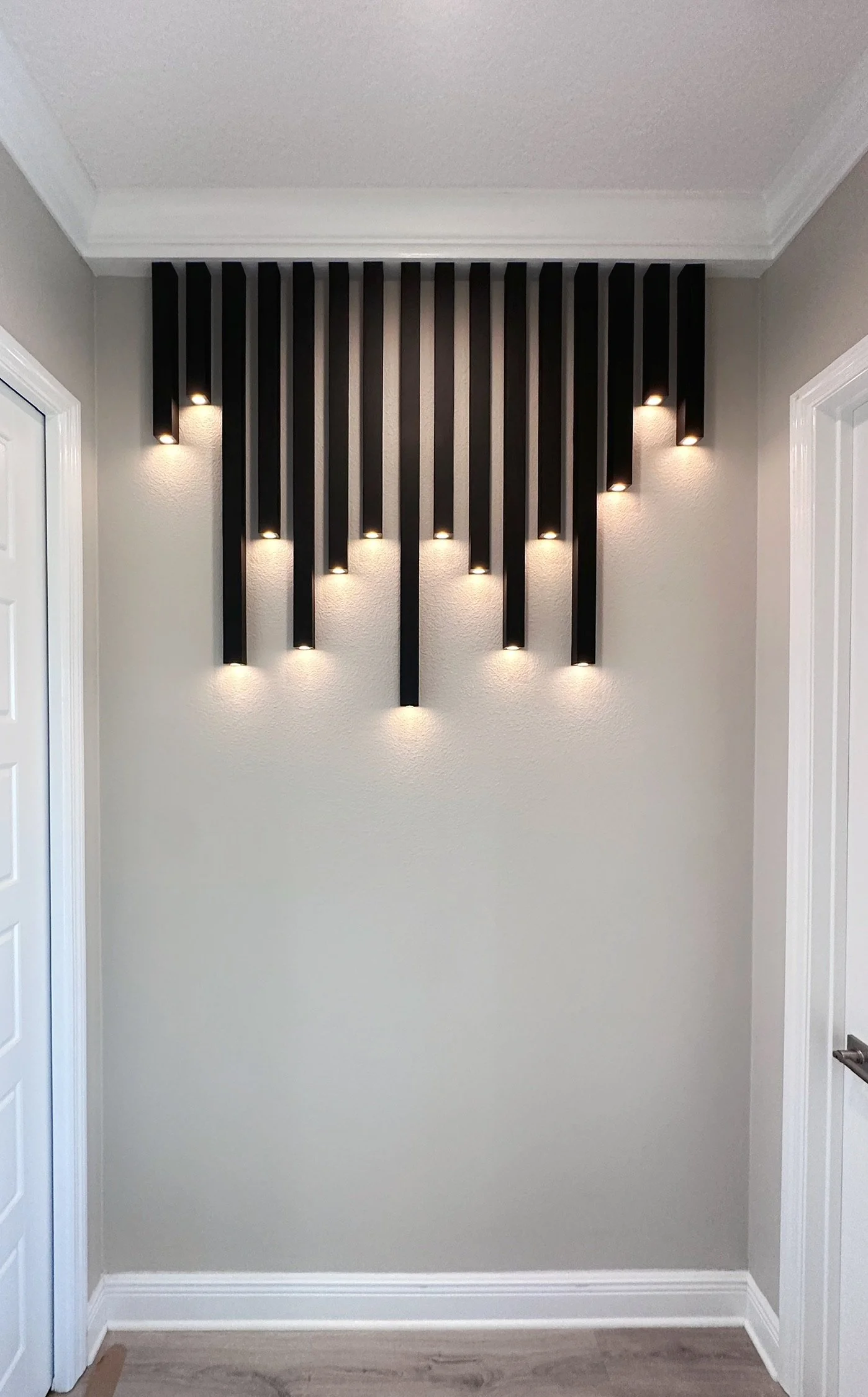 Modern wall-mounted black decorative panels with integrated lighting in an interior hallway.