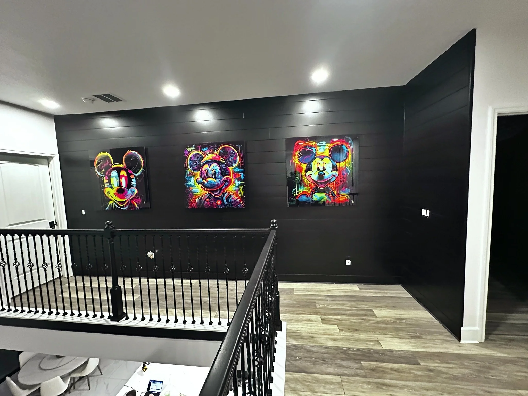 Three colorful neon-style artworks of Mickey Mouse characters are displayed on a black wall in a modern indoor space.