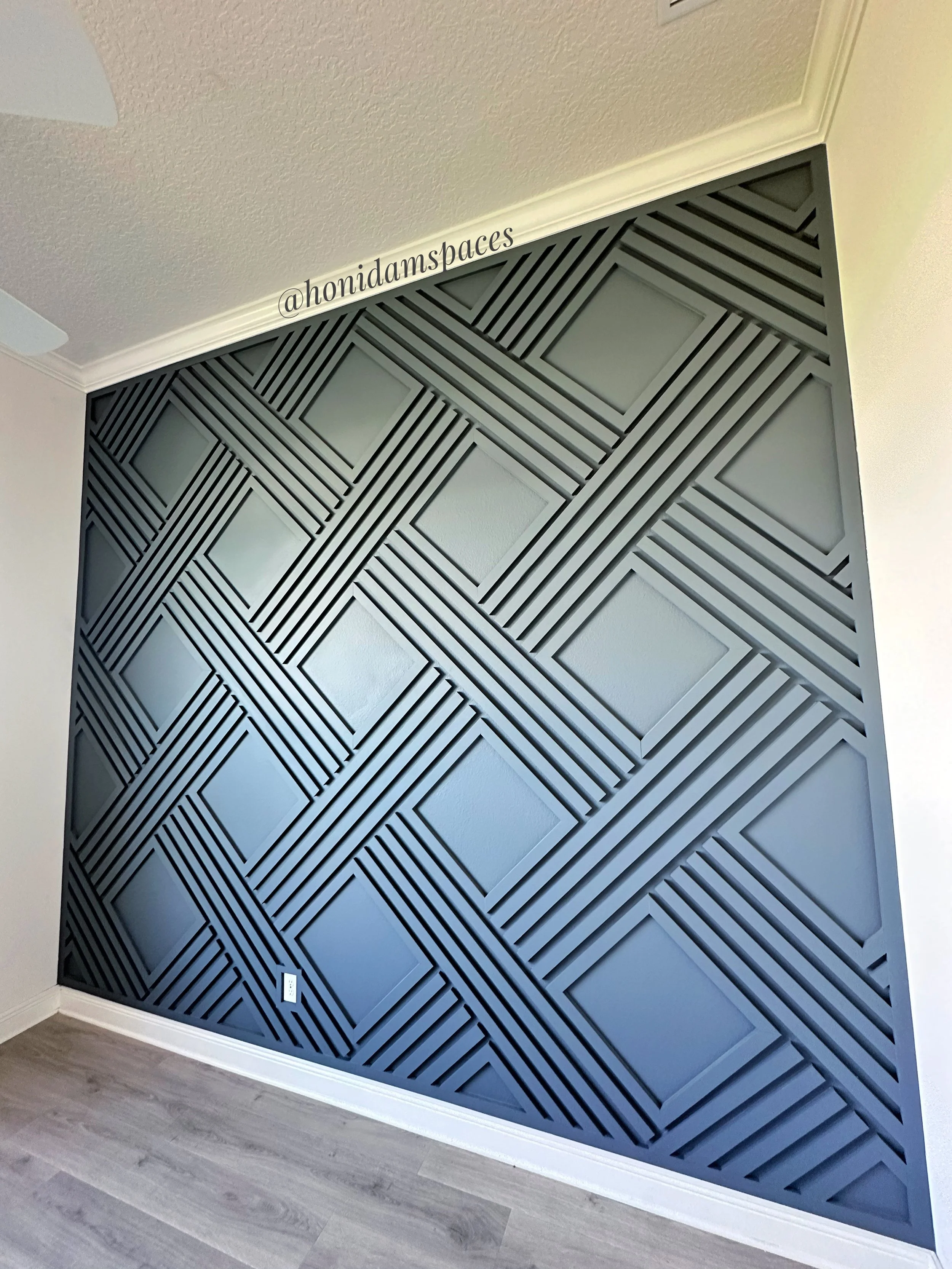 Decorative black wall with geometric pattern of intersecting lines and squares in a modern interior space.