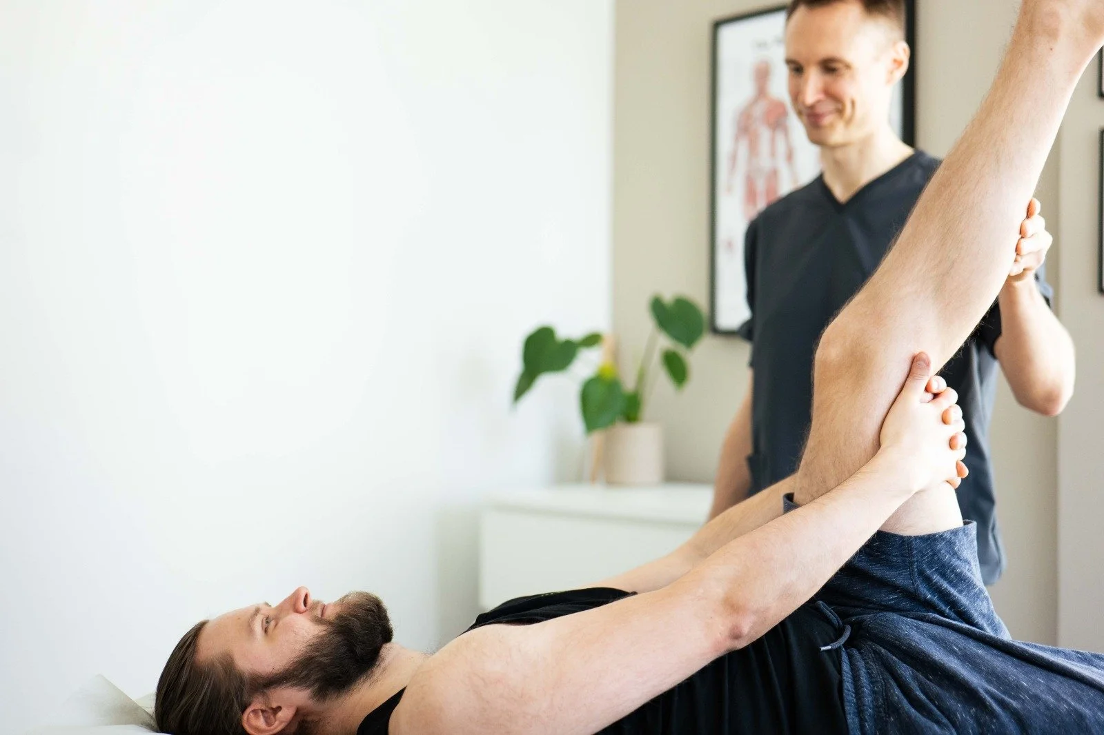 Physical therapist assisting a man with leg exercise in a wellness clinic.