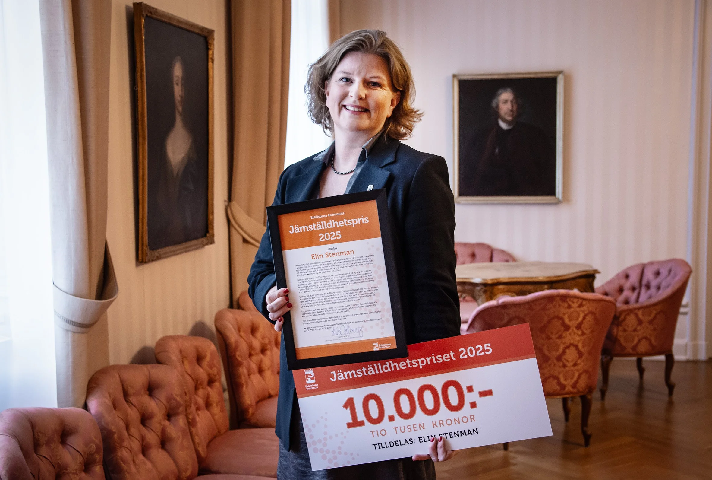 Elin Stenman står i Drottningrummet i Stadshuset, håller i diplom för Jämställdhetspriset och en stor check på 10.000 kronor