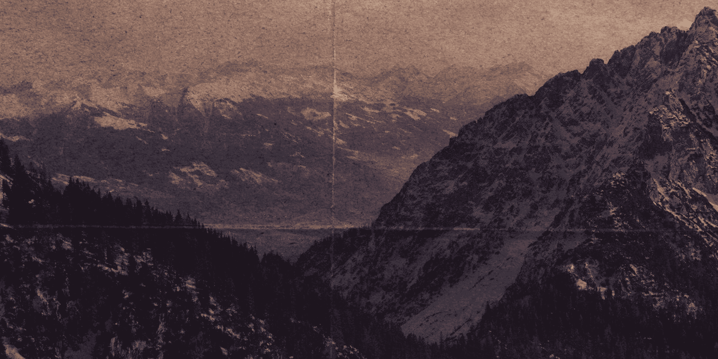 Mountain landscape with snow-capped peaks, forested slopes, and a glacier or lake in the valley.