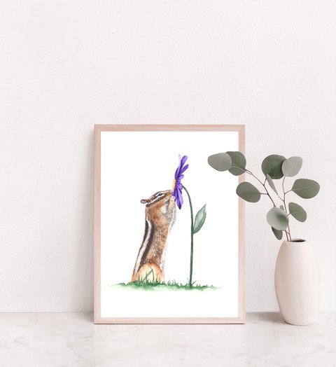 Framed picture of a cute animal with a purple bow on its head next to a plant in a white vase.