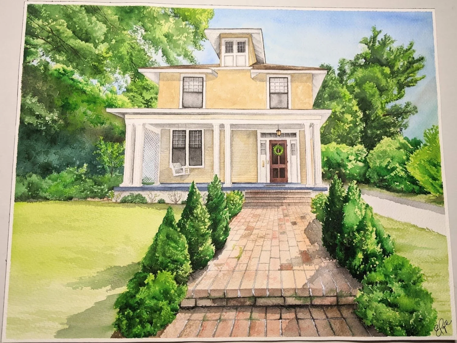 Watercolor painting of a vintage yellow two-story house with white trim, front porch with white columns, brick pathway leading to the front door, lush green trees and bushes surrounding the house, blue sky above.