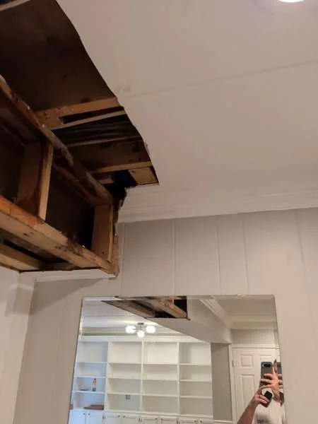 Drain line visible in opened ceiling cavity showing leak source