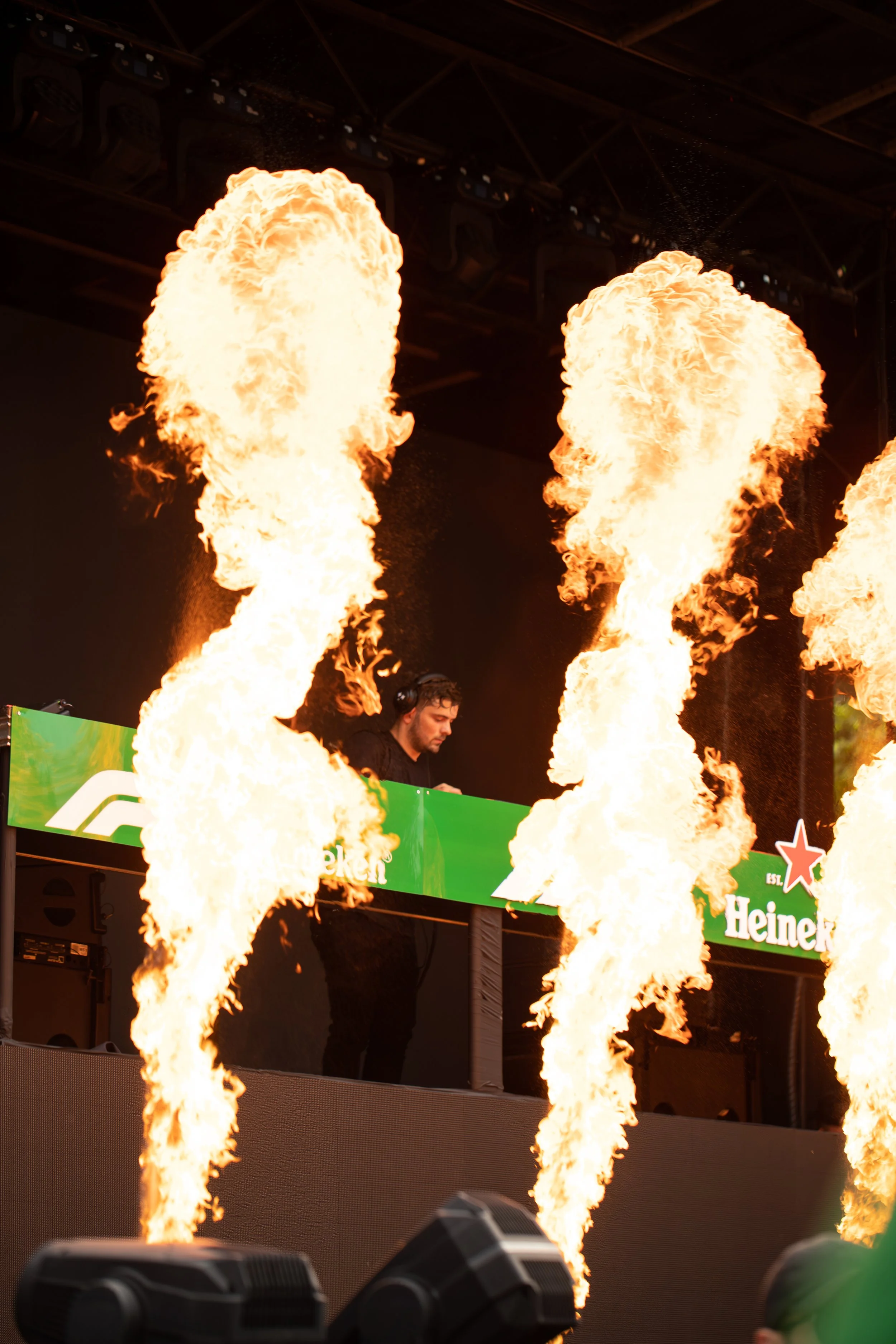 Martin Garrix performs on stage after the Canadian Formula 1 Grand Prix with flames shooting up in front of him during a live event, with branding from Heineken and Formula 1 visible.