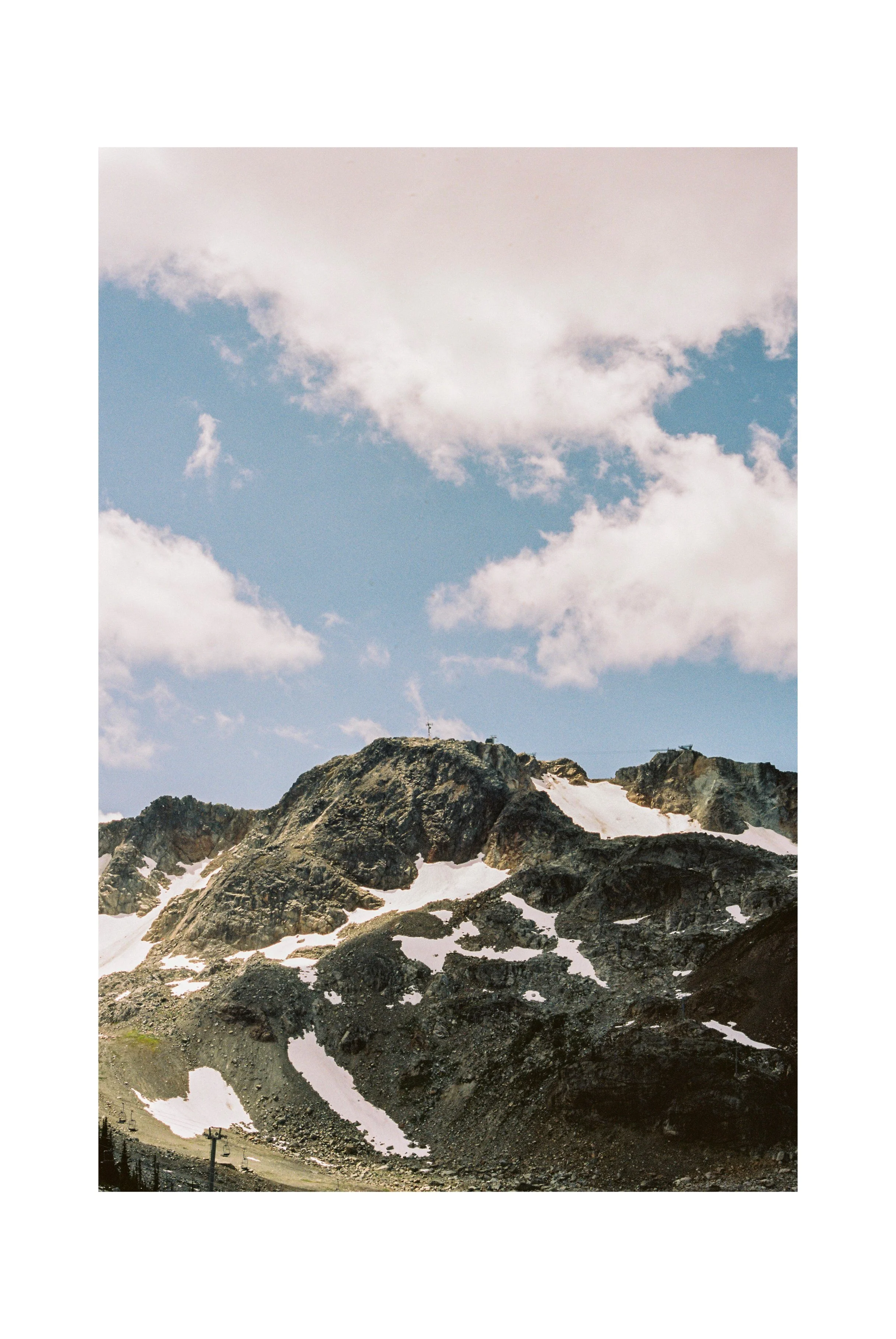Mountain with patches of snow under a partly cloudy sky. Whistler, BC. Shot on Kodak Gold 200. 