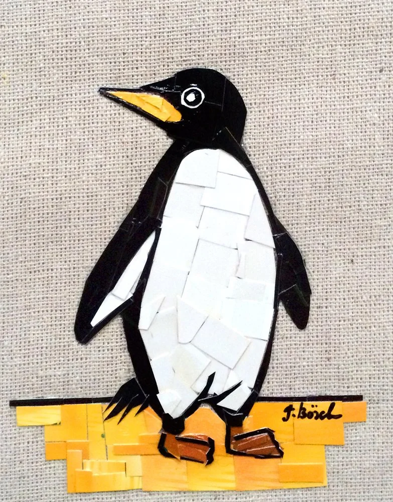 A collage of a penguin made from various cut-out pieces of paper or cardboard, standing on a yellow-orange base with the artist's signature.