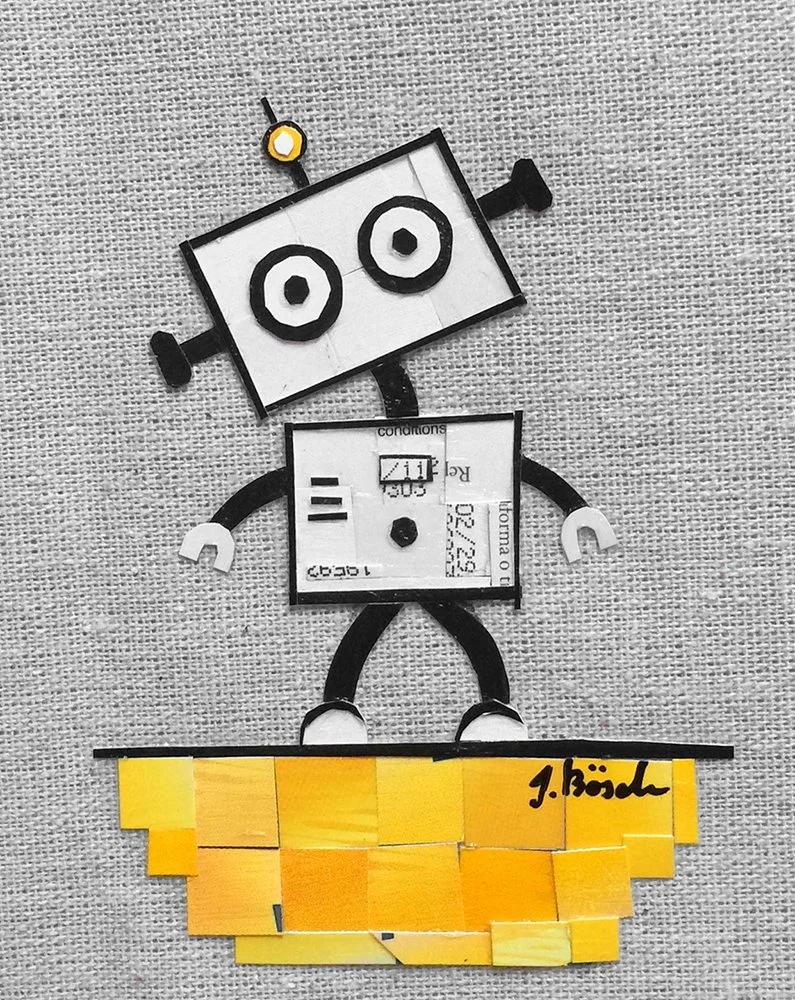 A robot made from various paper and cardboard pieces, with a rectangular head, square torso, and yellow block feet, lying on a textured surface.