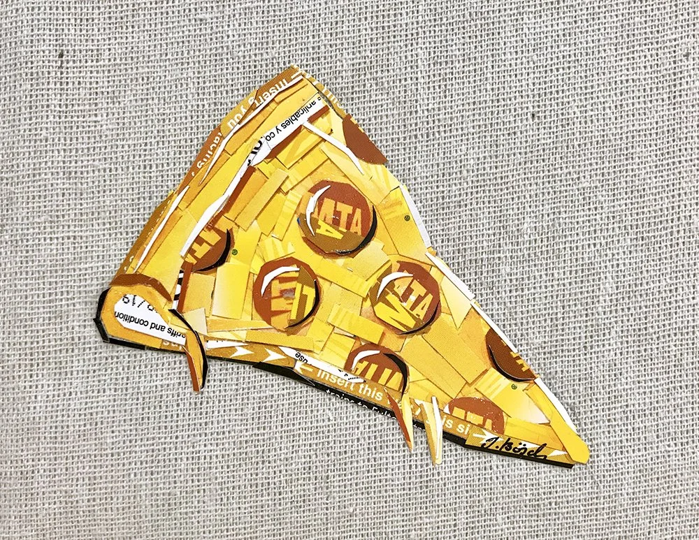 A three-dimensional model of a triangle made from yellow and orange cutouts, with printed text and circular logos, laying on a textured gray surface.