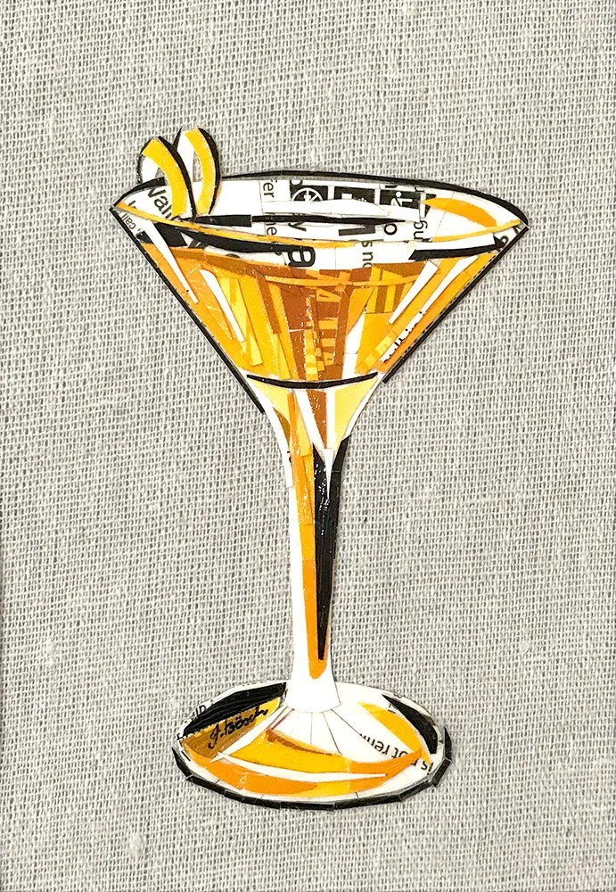 Artistic collage of a Martini glass with a lemon wedge, made from cutout magazine text, on a gray textured background.