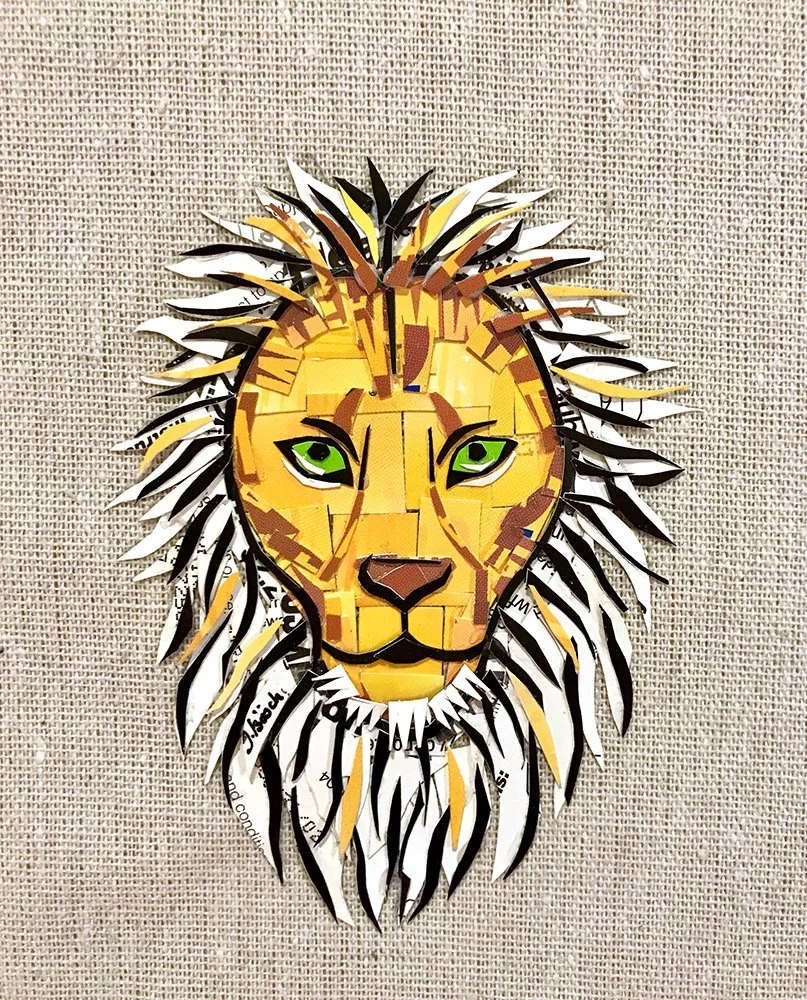 Colorful paper collage of a lion's face with green eyes and a detailed mane against a textured beige background.