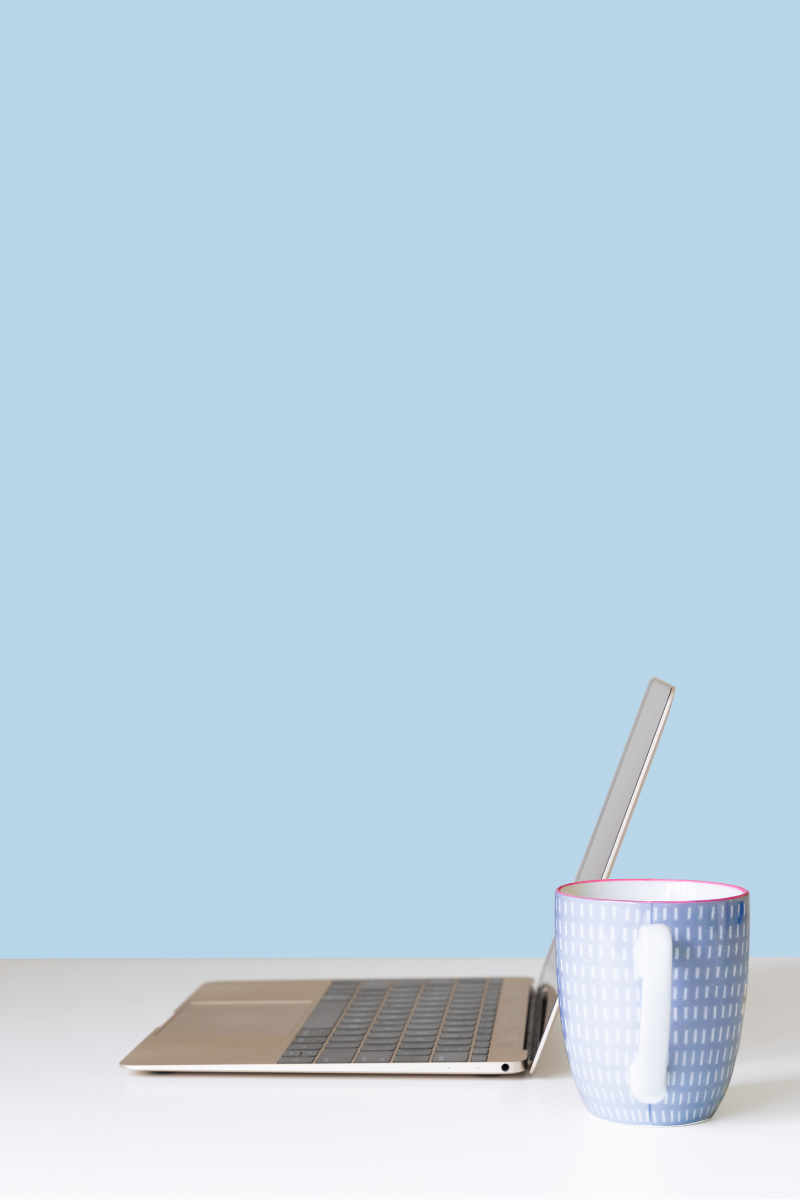 Laptop computer on a white desk next to a mug.
