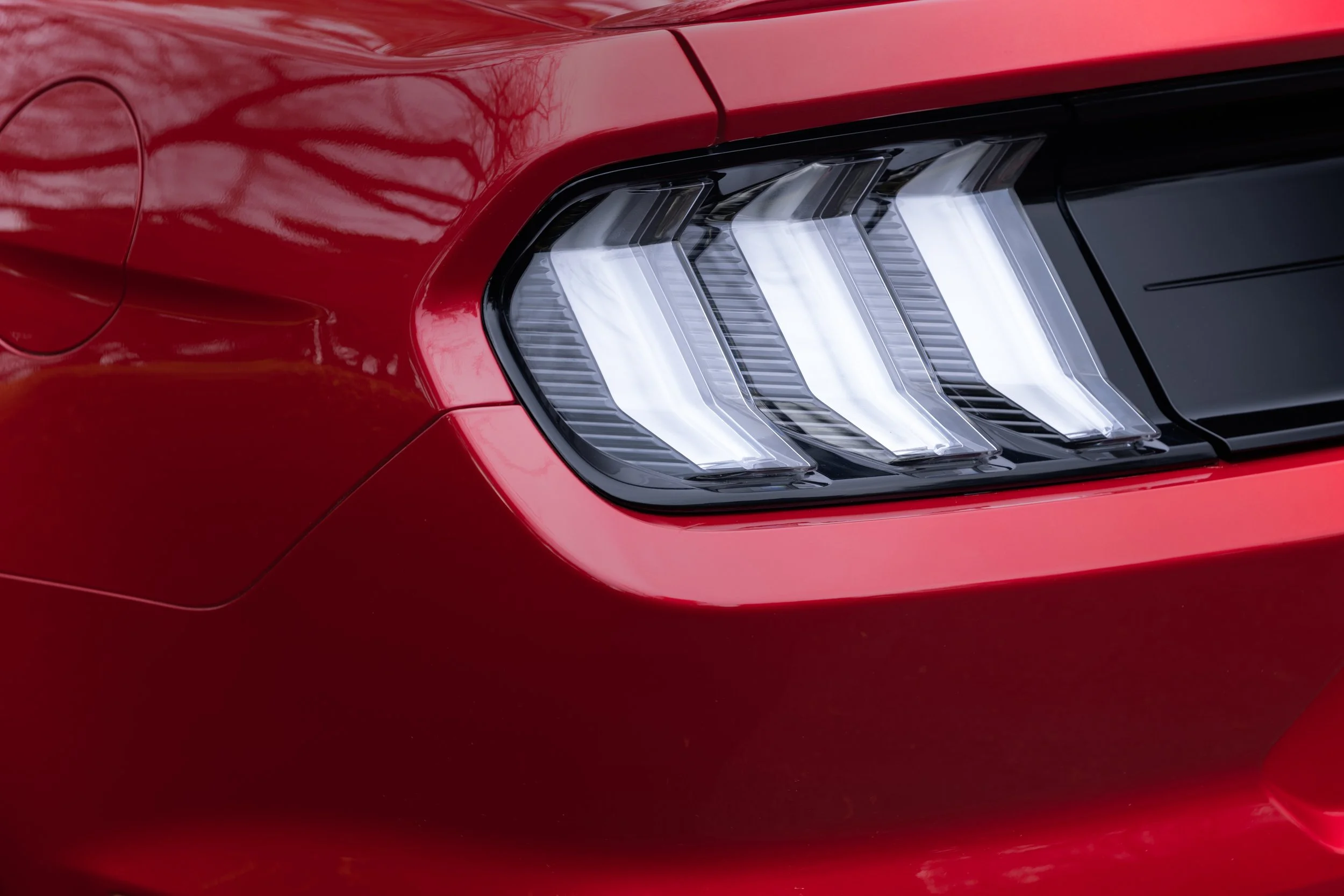 Close-up of the red rear end of a modern car, showing the taillight with three elongated, angled LED sections.
