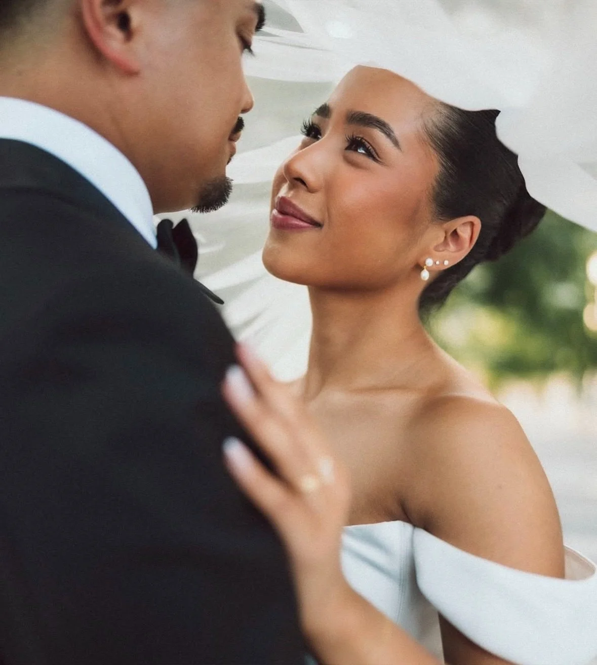 A bride and groom sharing an intimate moment on their wedding day, gazing into each other's eyes, with the bride smiling softly.