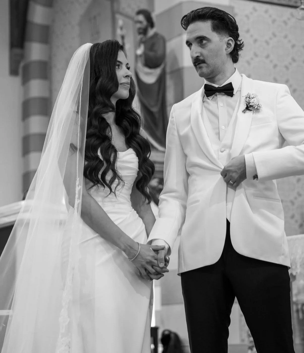 A bride and groom holding hands during their wedding ceremony in a church.