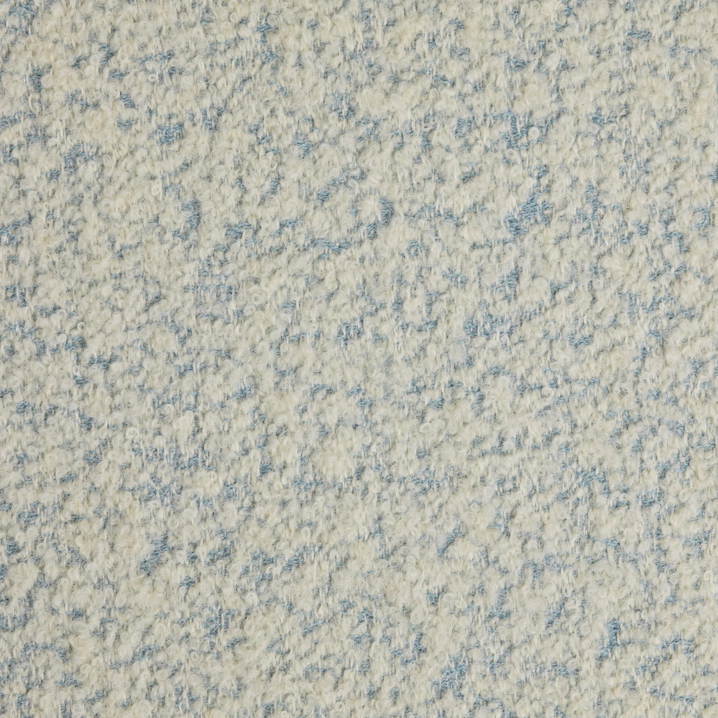 Close-up of a light-colored textured carpet with a mix of cream and light blue fibers.